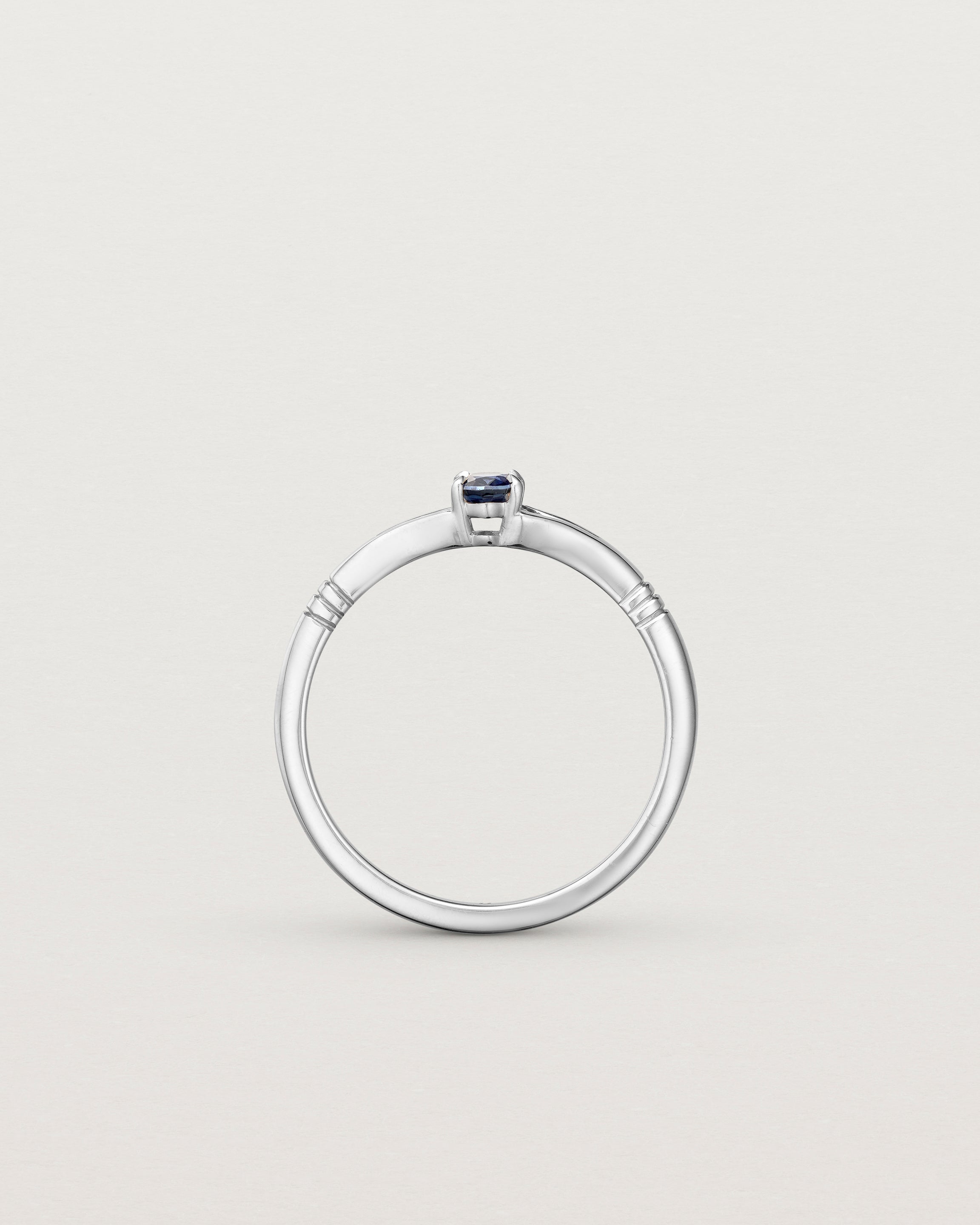 Standing deep etched image of a white gold engagement ring with an oval sapphire stone