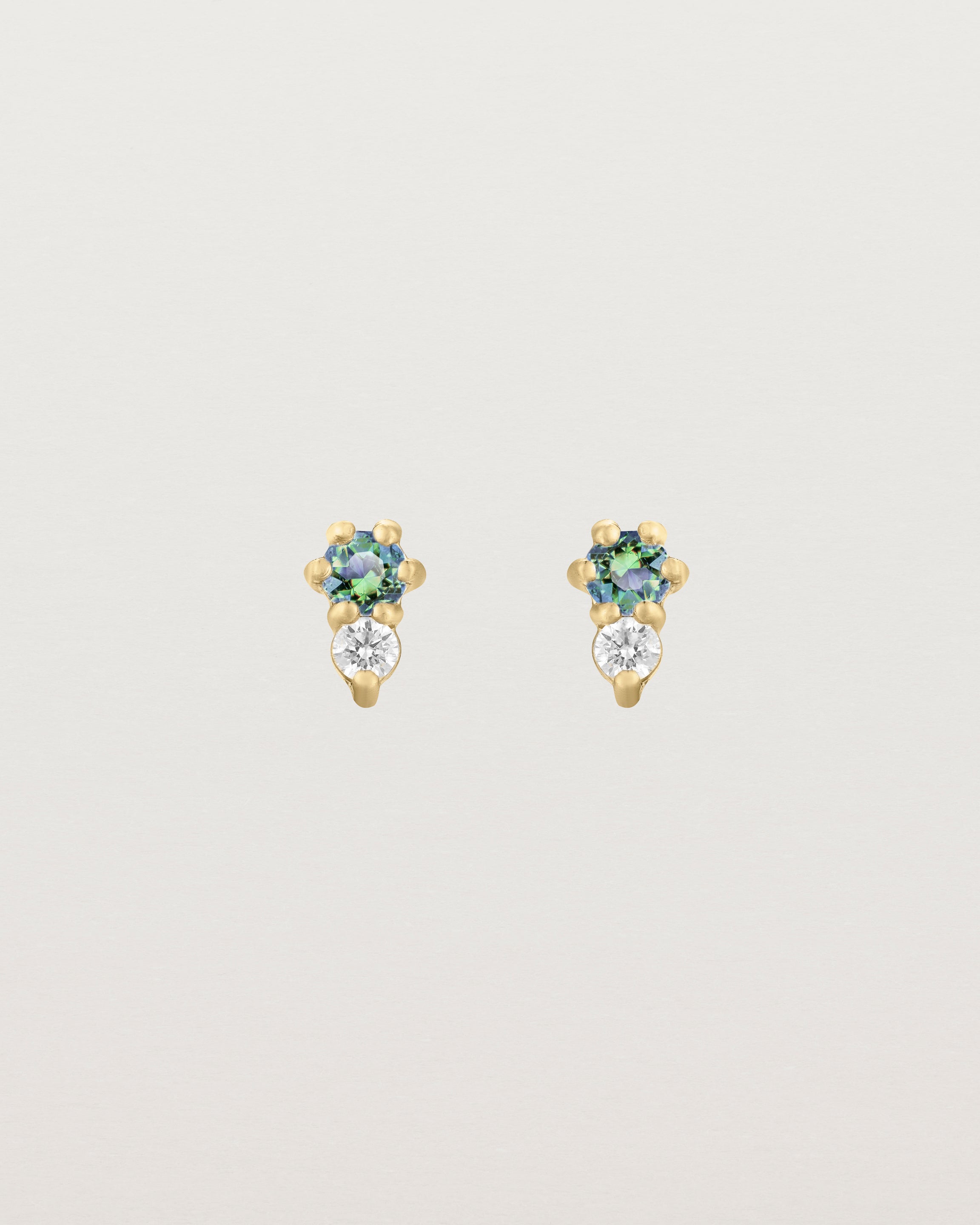 Front facing deep etched image of a pair of yellow gold earrings with alexandrite birthstones and diamonds.