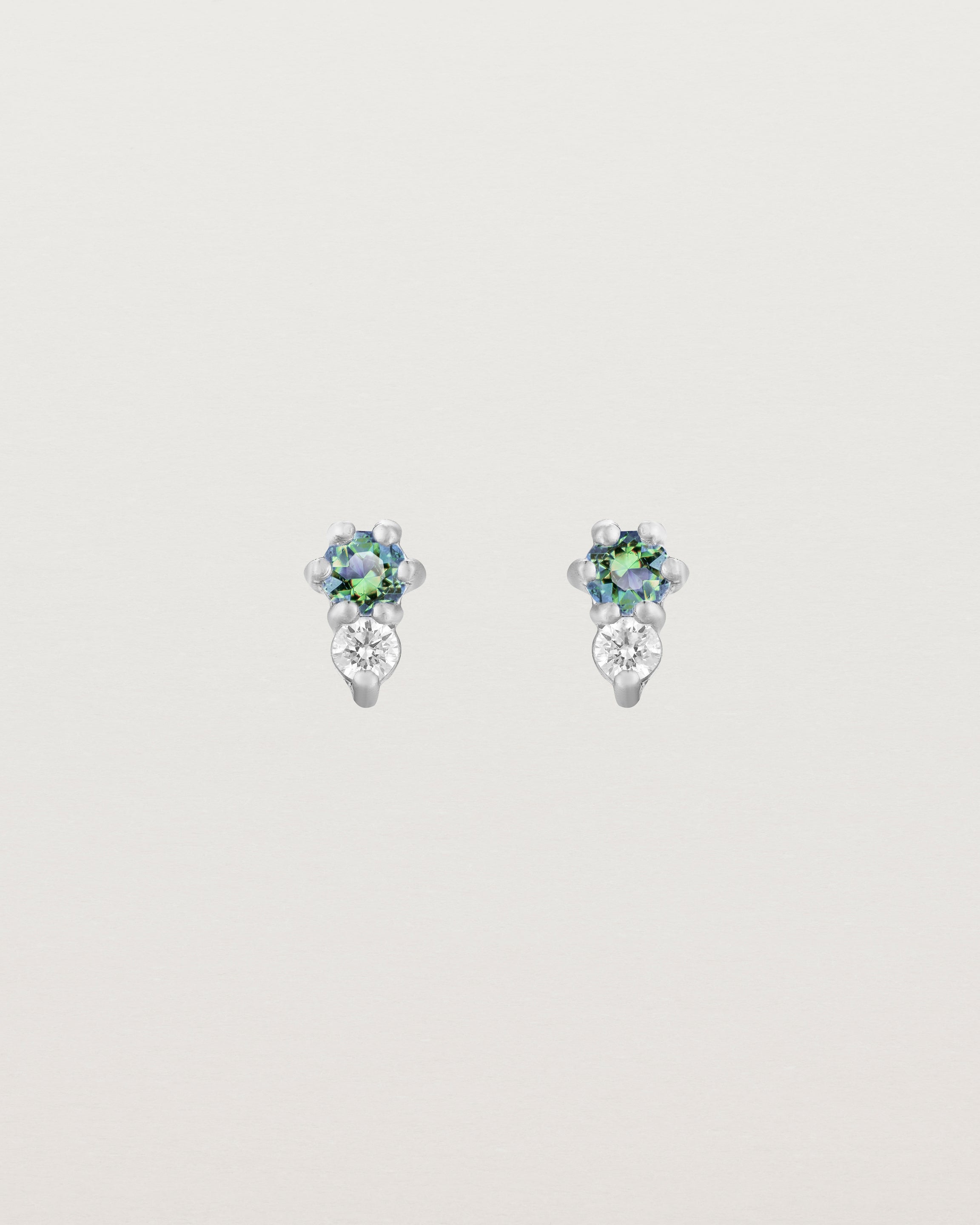 Front facing deep etched image of a pair of white gold earrings with alexandrite birthstones and diamonds.