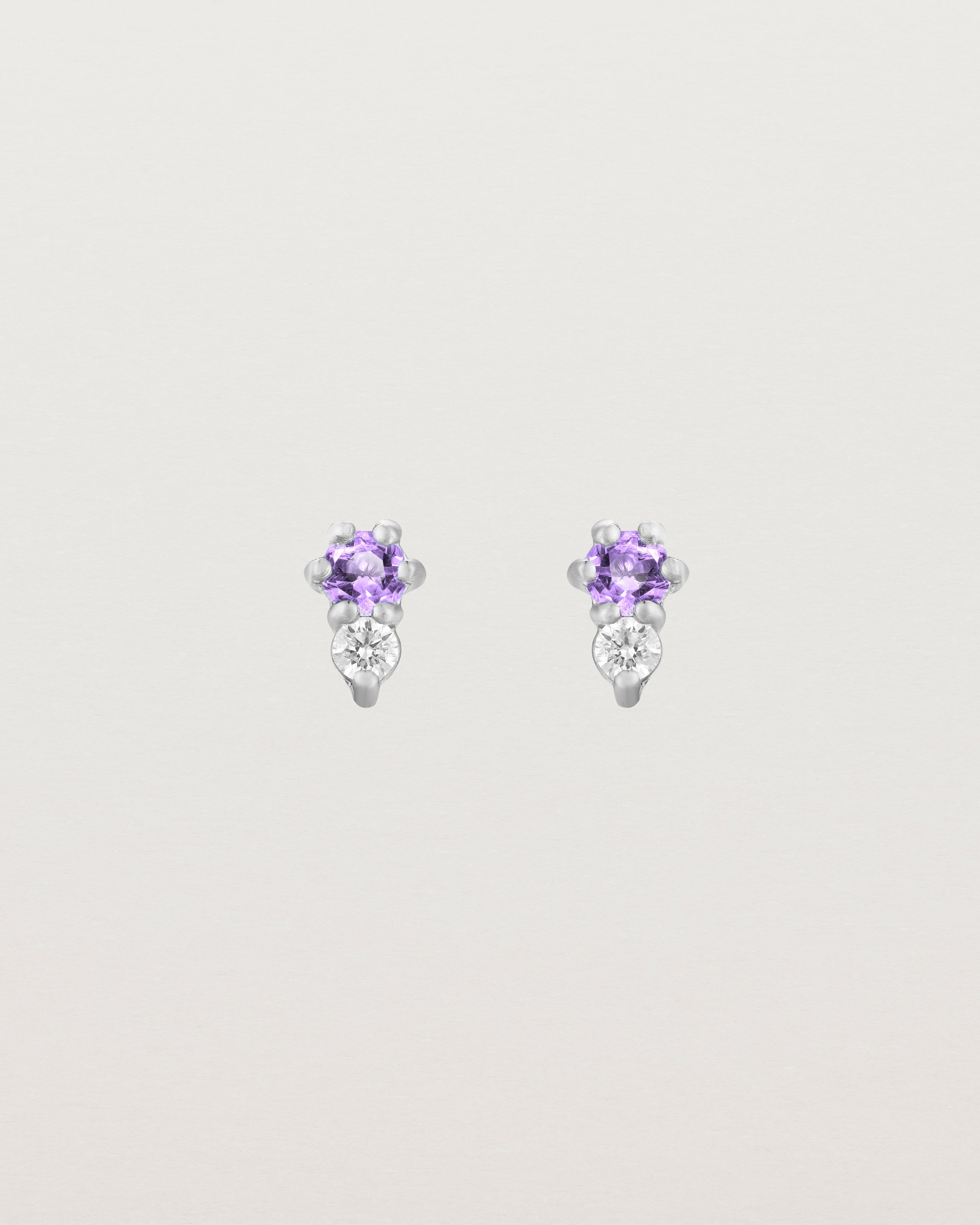 Front facing deep etched image of a pair of white gold earrings with amethyst birthstones and diamonds.