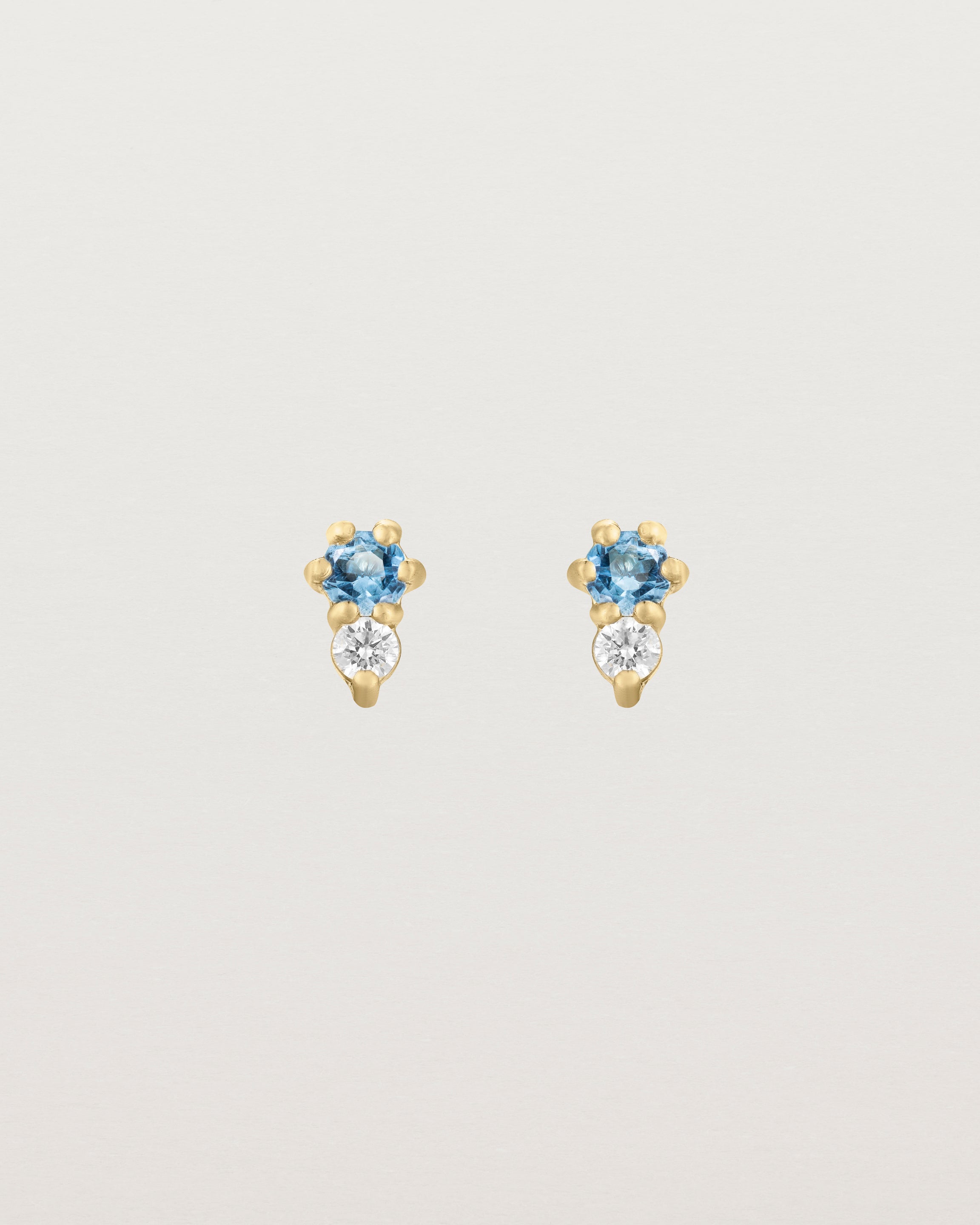 Front facing deep etched image of a pair of yellow gold earrings with aquamarine birthstones and diamonds.