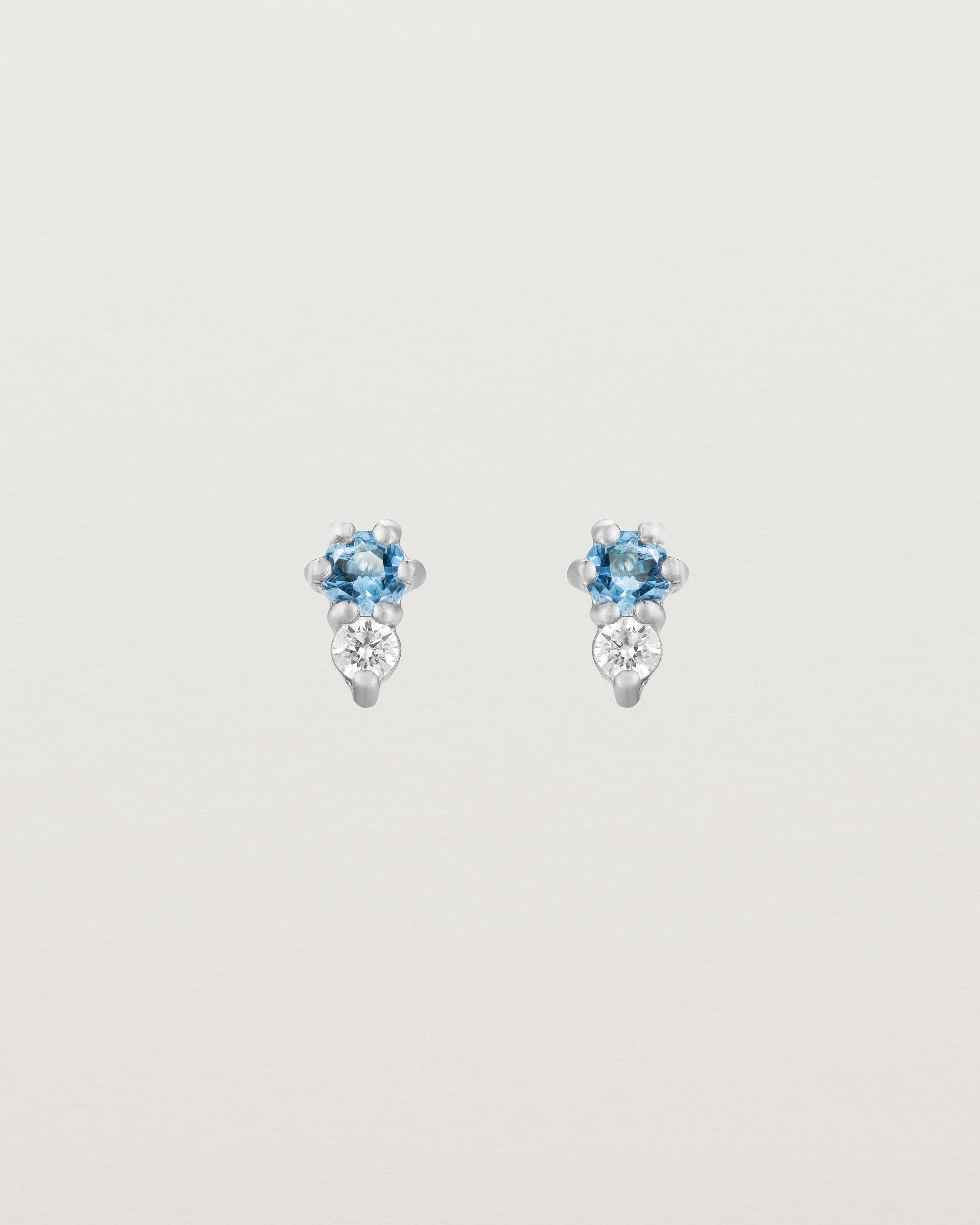 Front facing deep etched image of a pair of white gold earrings with aquamarine birthstones and diamonds.