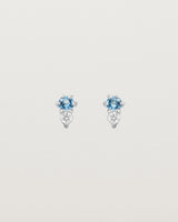 Front facing deep etched image of a pair of white gold earrings with aquamarine birthstones and diamonds.