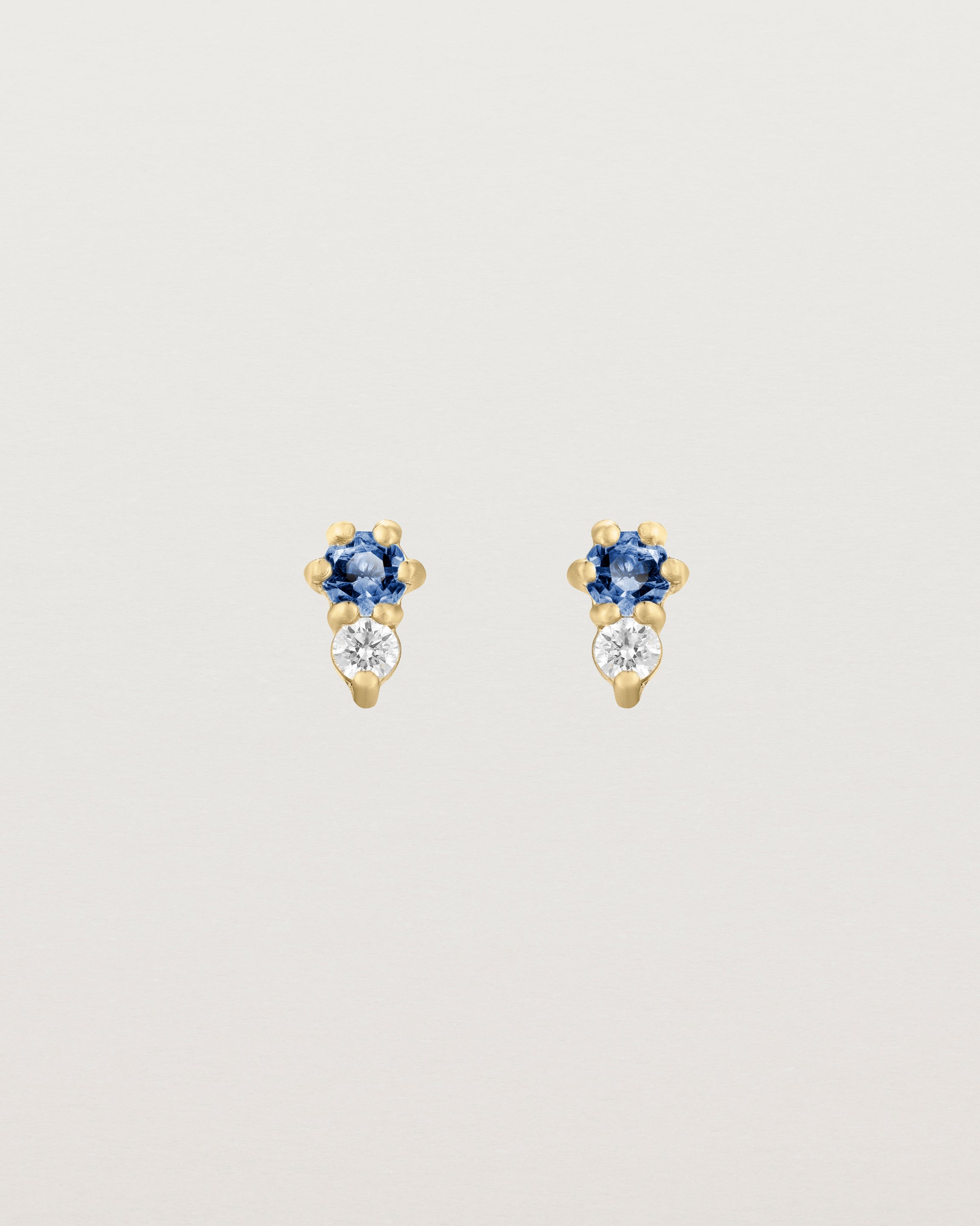 Front facing deep etched image of a pair of yellow gold earrings with blue sapphire birthstones and diamonds.