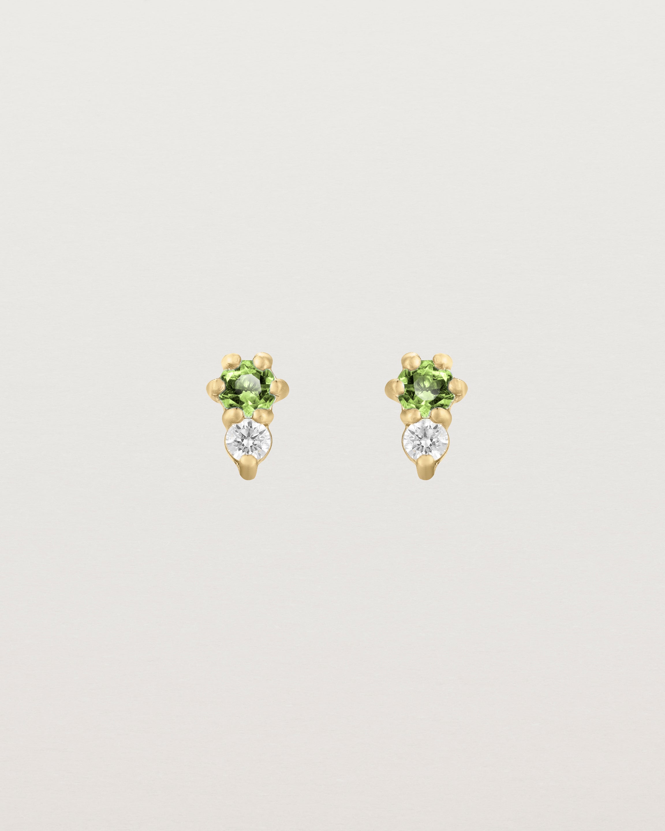 Front facing deep etched image of a pair of yellow gold earrings with peridot birthstones and diamonds.