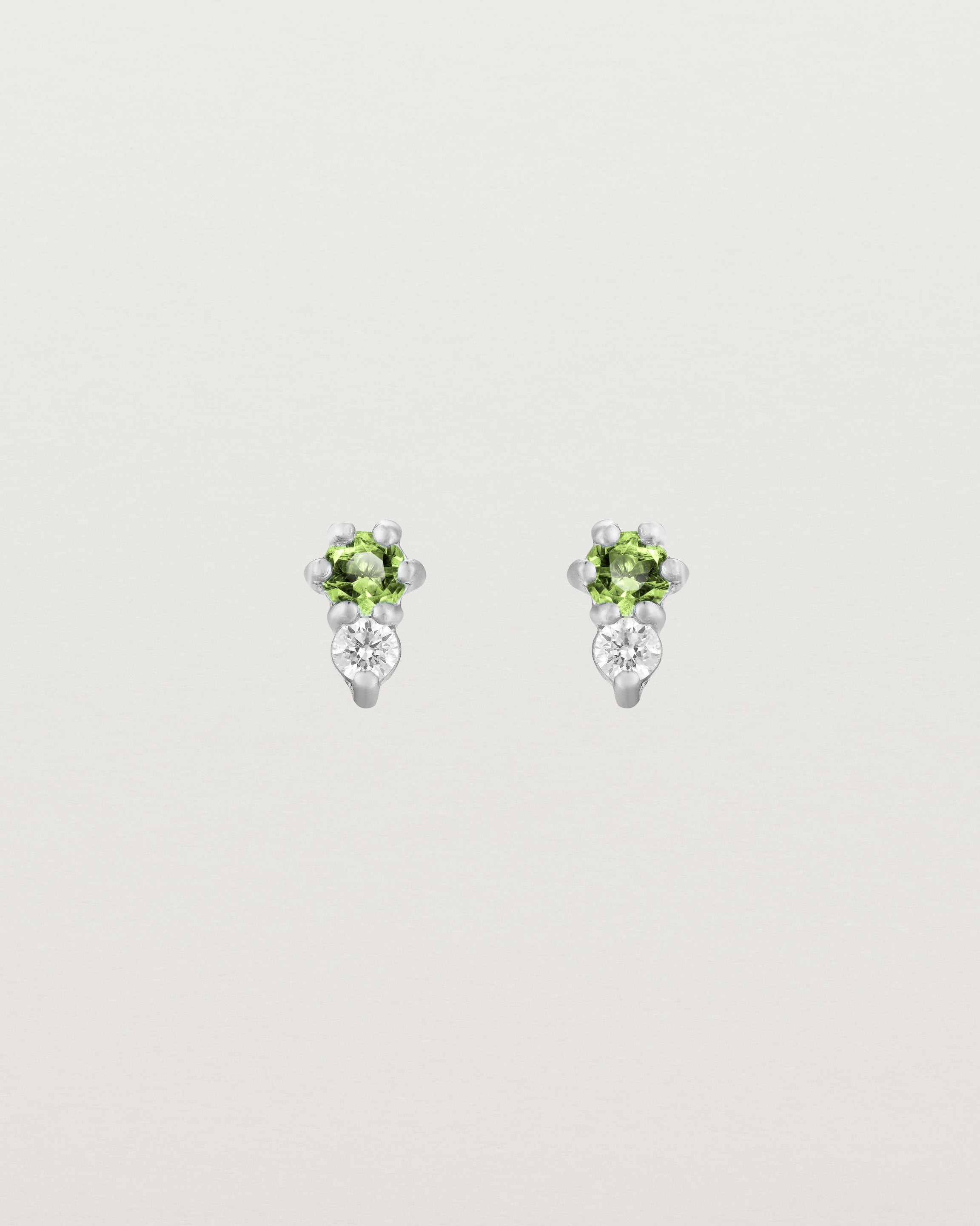 Front facing deep etched image of a pair of white gold earrings with peridot birthstones and diamonds.