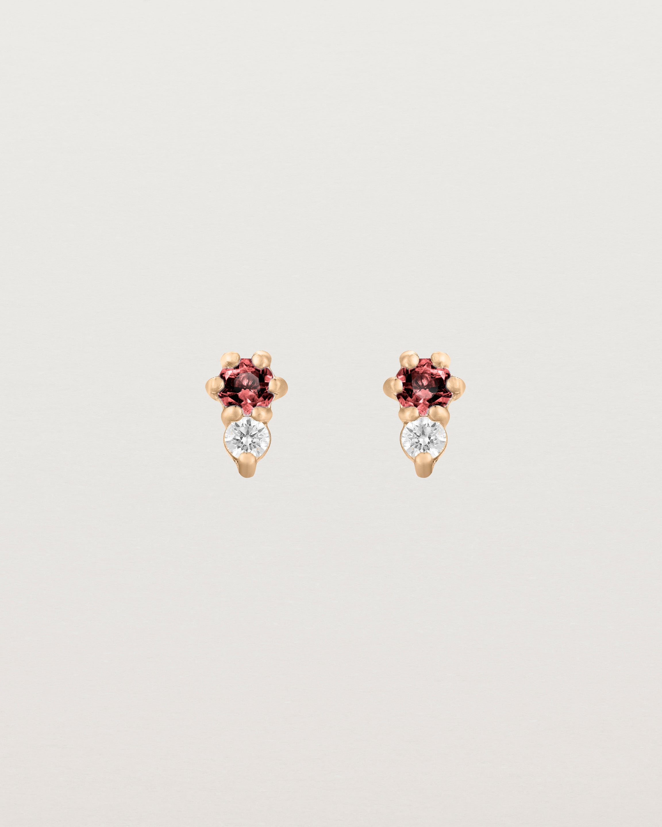 Front facing deep etched image of a pair of rose gold earrings with garnet birthstones and diamonds.