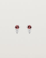 Front facing deep etched image of a pair of white gold earrings with garnet birthstones and diamonds.