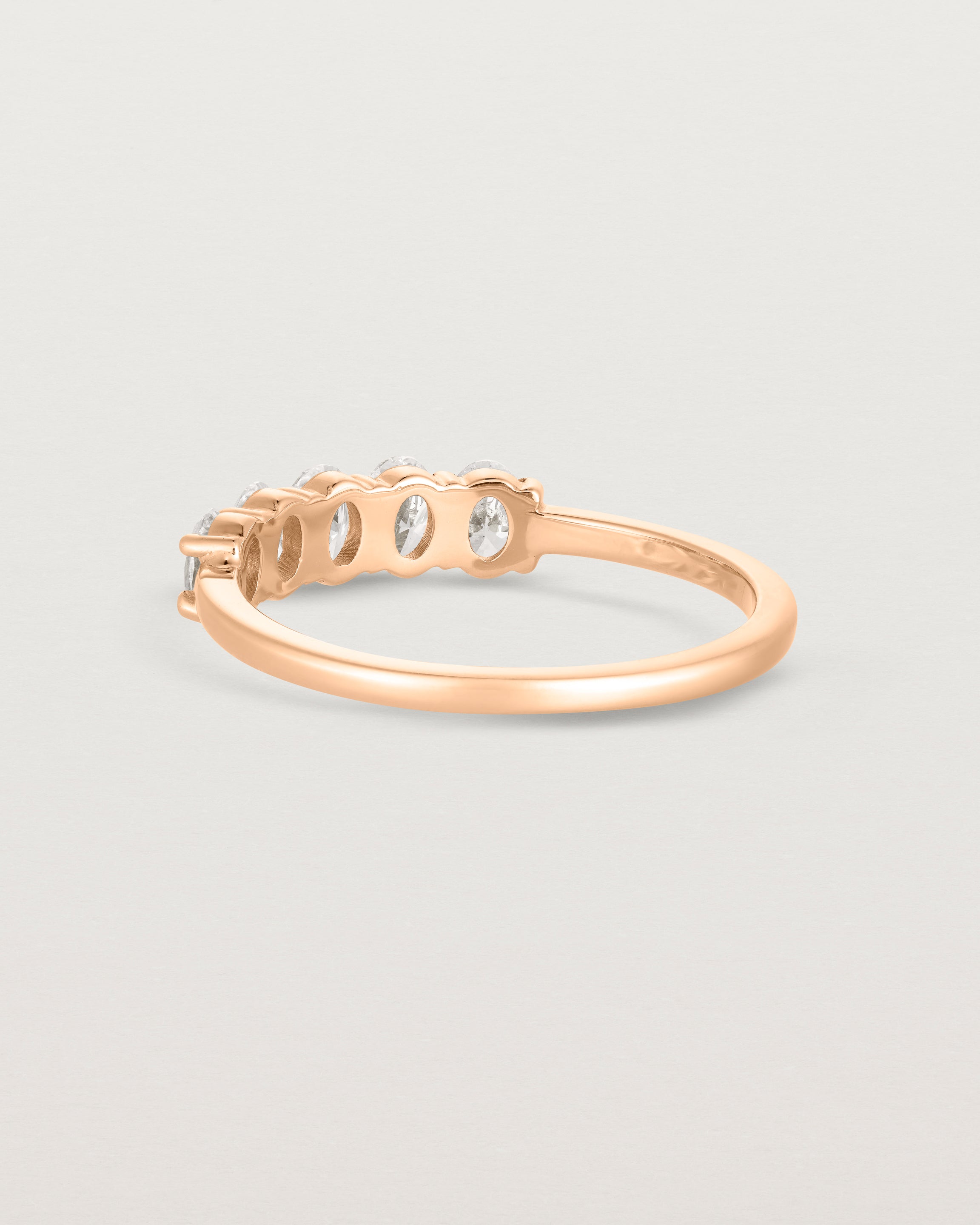 Back facing deep etched image of a rose gold wrap engagement ring with five oval diamonds.