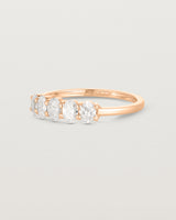 Side on deep etched image of a rose gold wrap engagement ring with five oval diamonds.