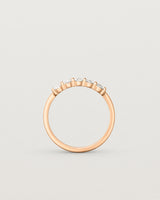 Standing deep etched image of a rose gold wrap engagement ring with five oval diamonds.