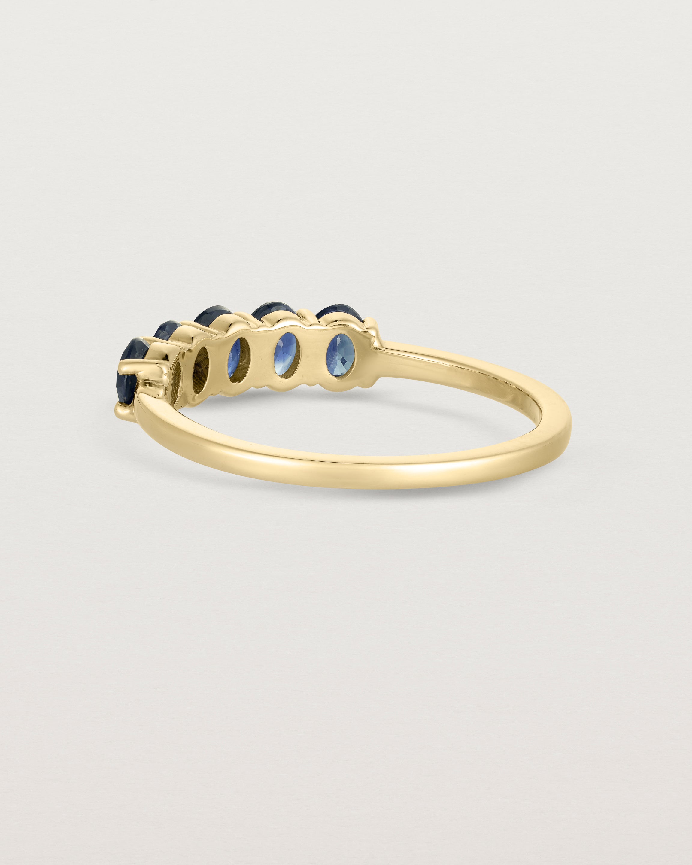 Back facing  deep etched image of a yellow gold wrap engagement ring with five Sapphire Stones.