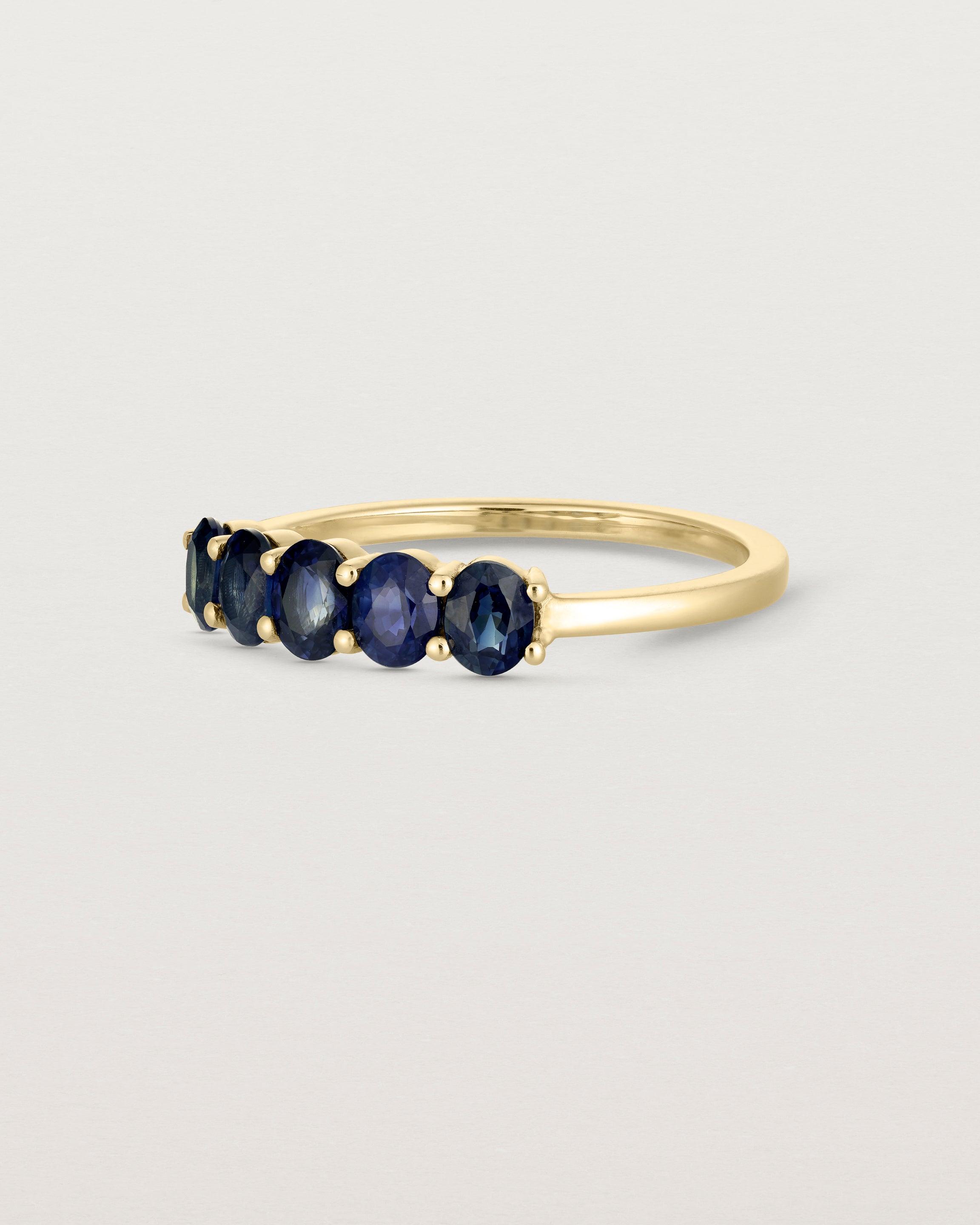 Side on deep etched image of a yellow gold wrap engagement ring with five Sapphire Stones.