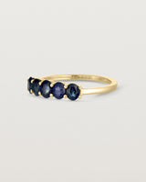 Side on deep etched image of a yellow gold wrap engagement ring with five Sapphire Stones.