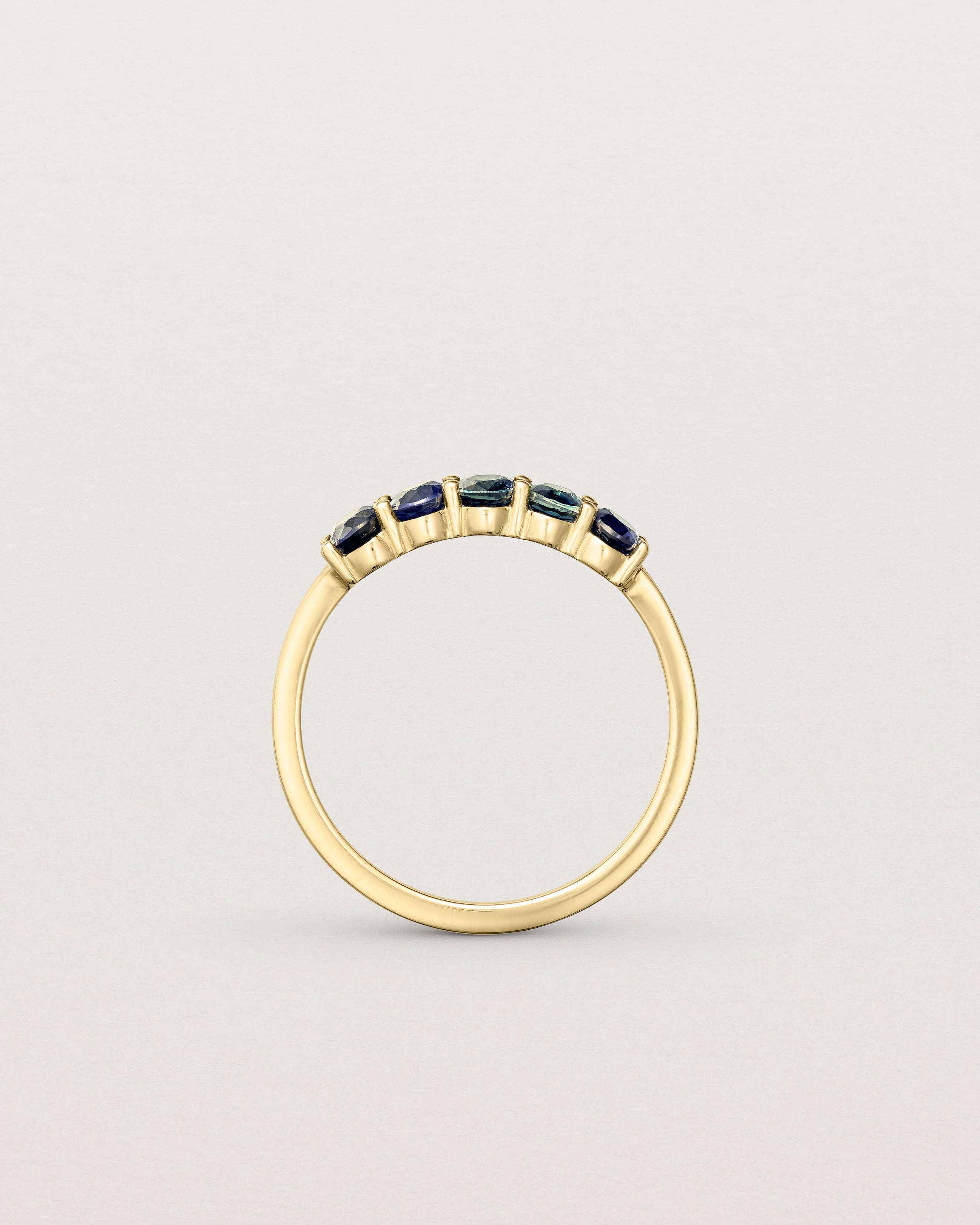 Standing deep etched image of a yellow gold wrap engagement ring with five Sapphire Stones.