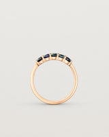 Standing deep etched image of a rose gold wrap engagement ring with five Sapphire Stones.