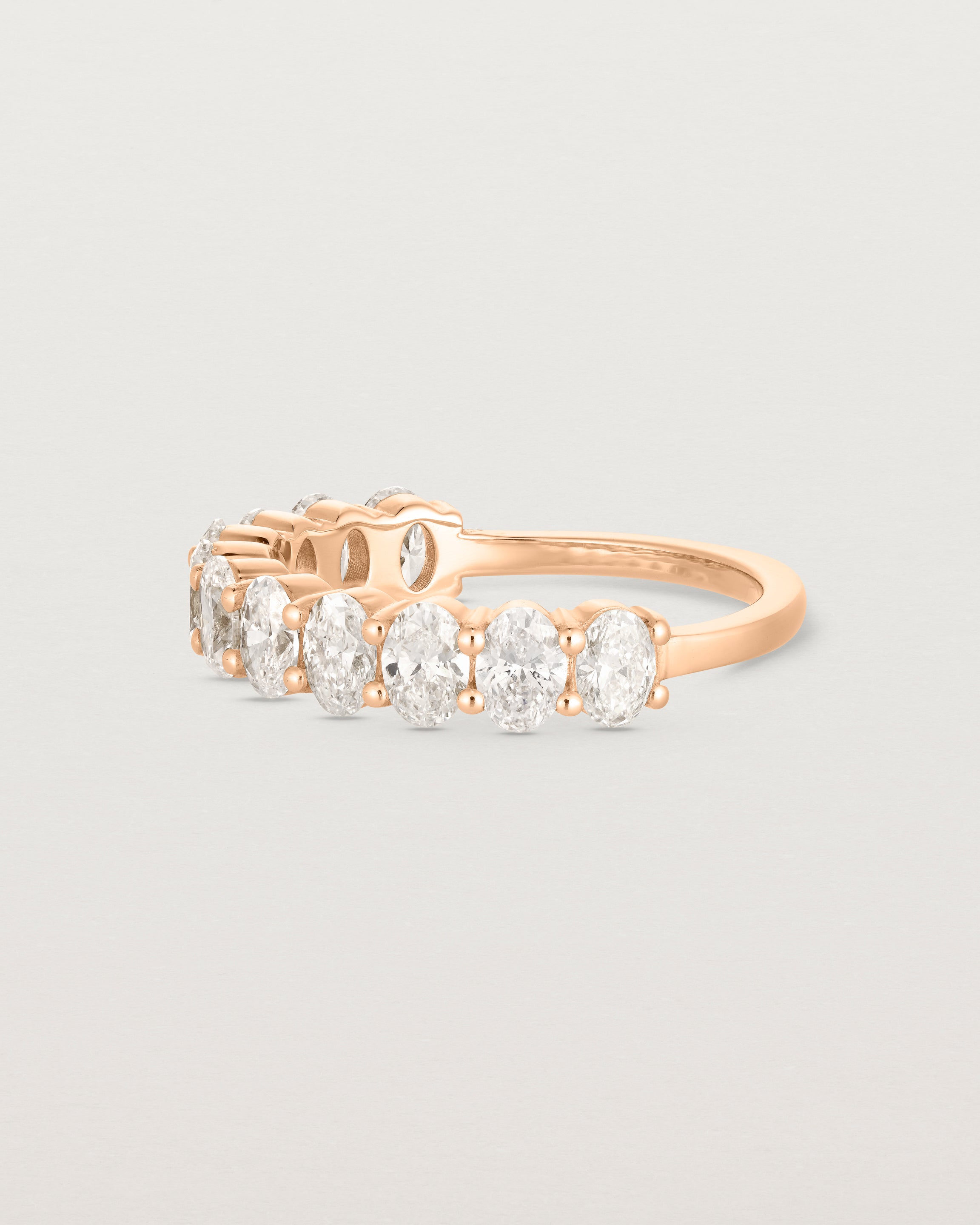 Side facing on deep etched image of a rose gold wrap engagement ring with 11 white diamonds.