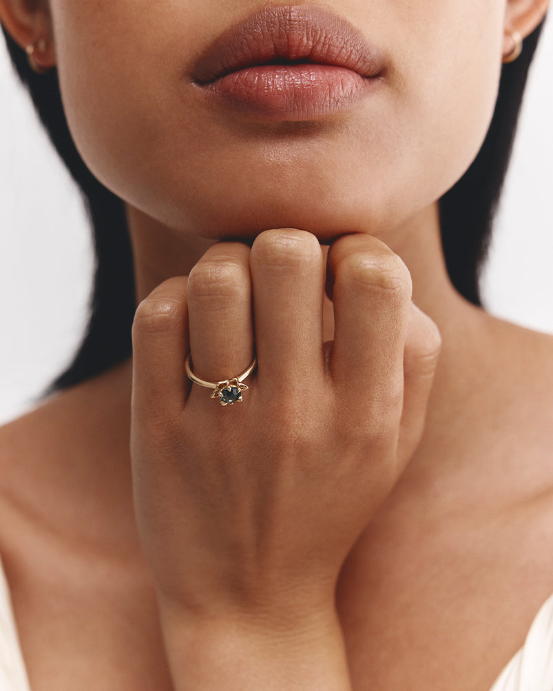 Woman wearing  a Australian Teal Sapphire solitaire engagement ring. 