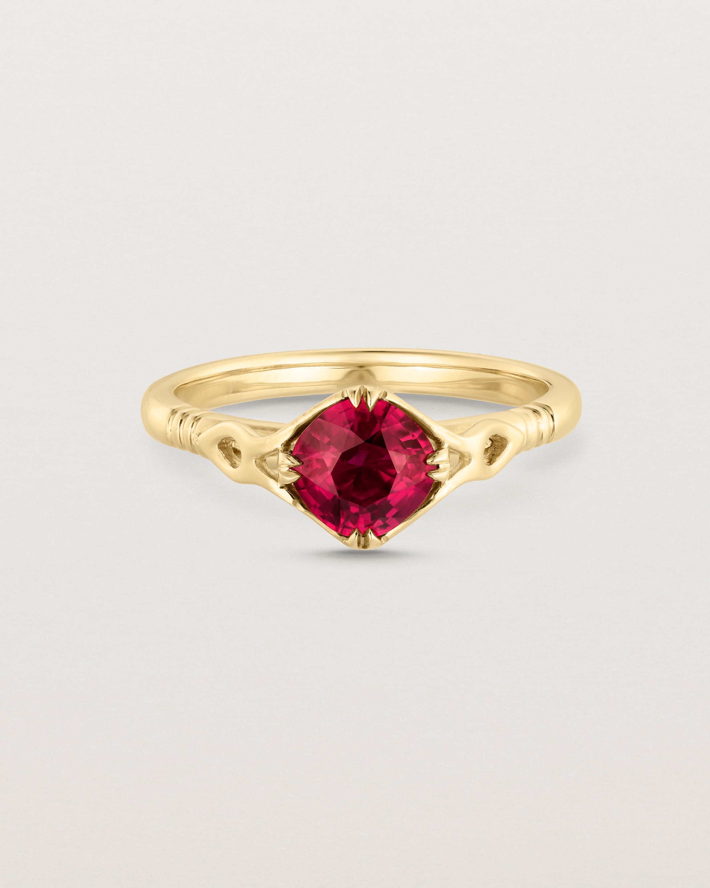 Front facing deep etched image of a yellow gold vintage inspired ring with a cushion cut ruby.