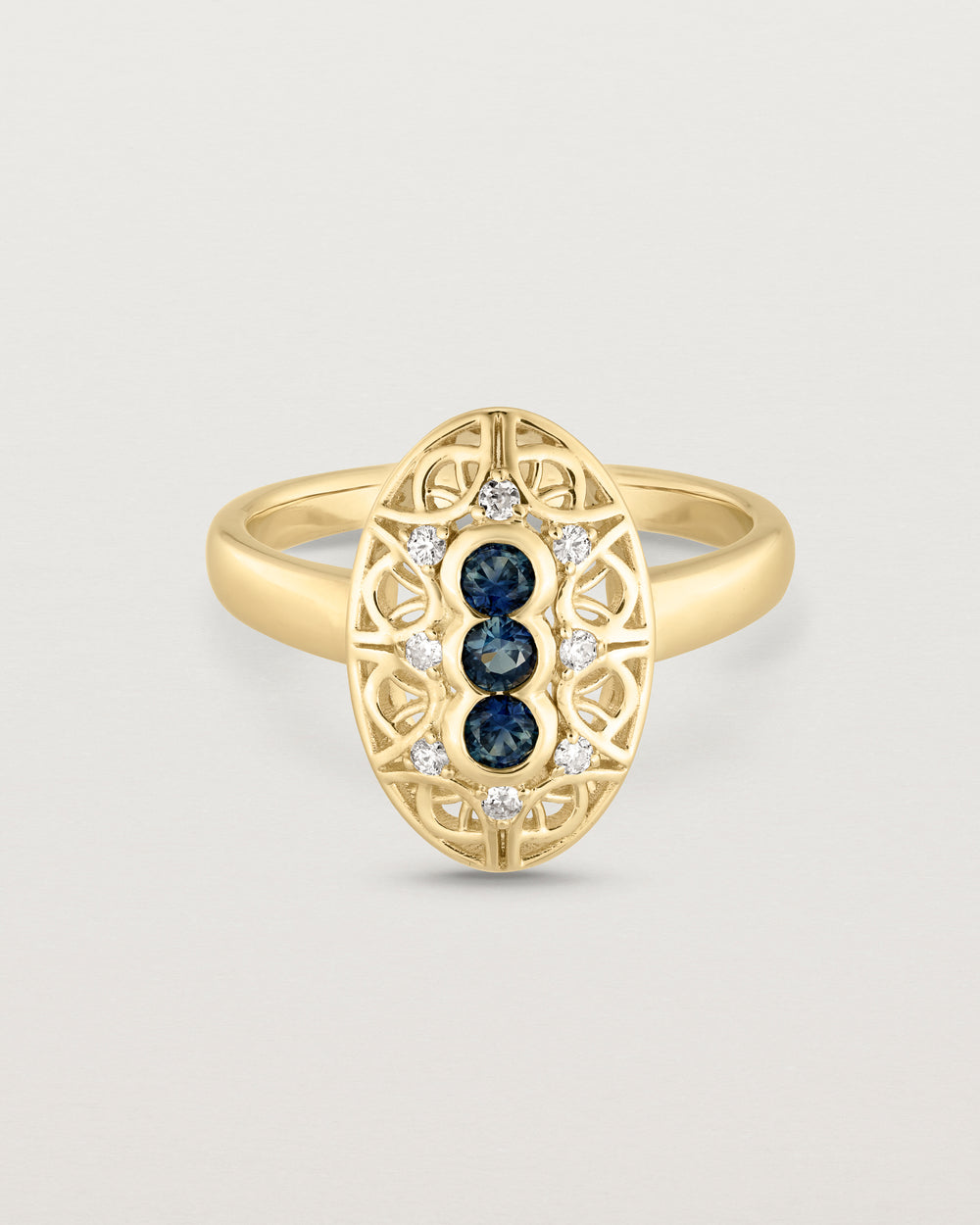 Front facing deep etched image of a yellow gold vintage inspired shield ring with three Australian sapphires and surrounded by eight old cut white diamonds.