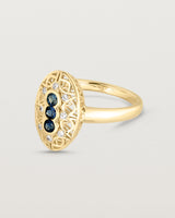 Side facing deep etched image of a yellow gold vintage inspired shield ring with three Australian sapphires and surrounded by eight old cut white diamonds.