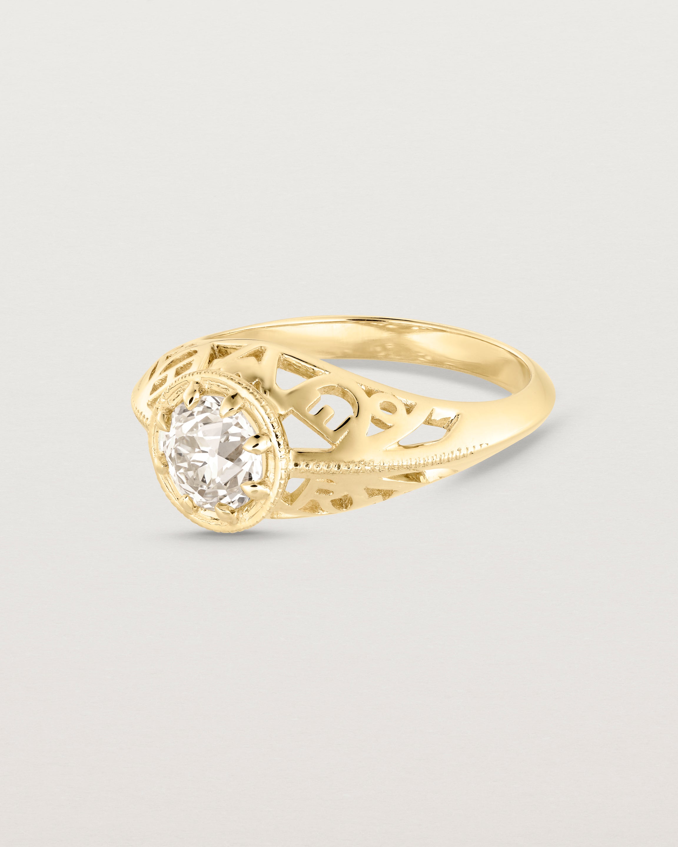 Side facing deep etched image of a yellow gold vintage inspired ring with old mine cut diamond, framed by an intricate filagree inspired gallery.