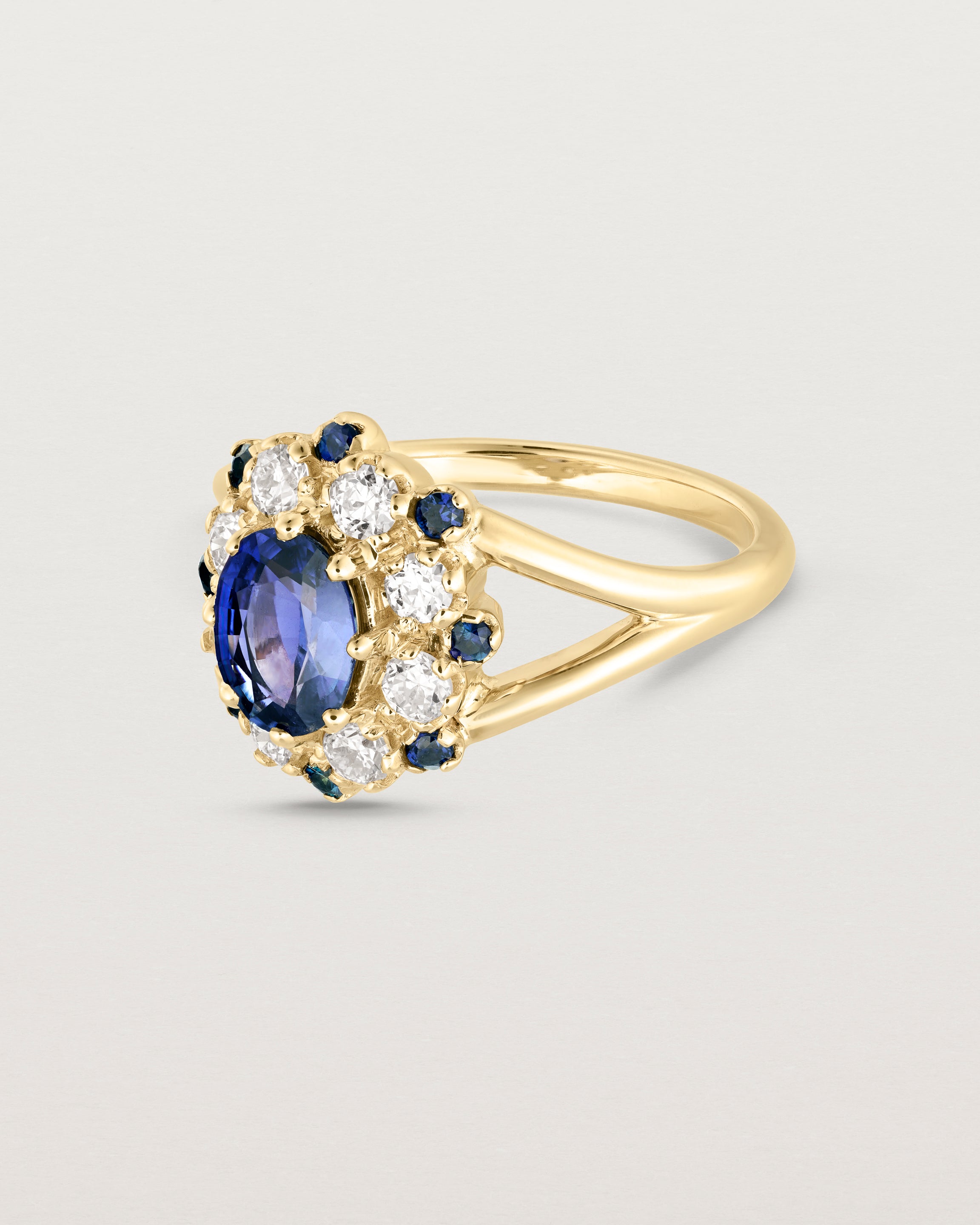 Side facing deep etched image of a yellow gold vintage inspired ring with an oval Ceylon Sapphire and a tiered halo of Old Cut Diamonds and Australian Sapphires.