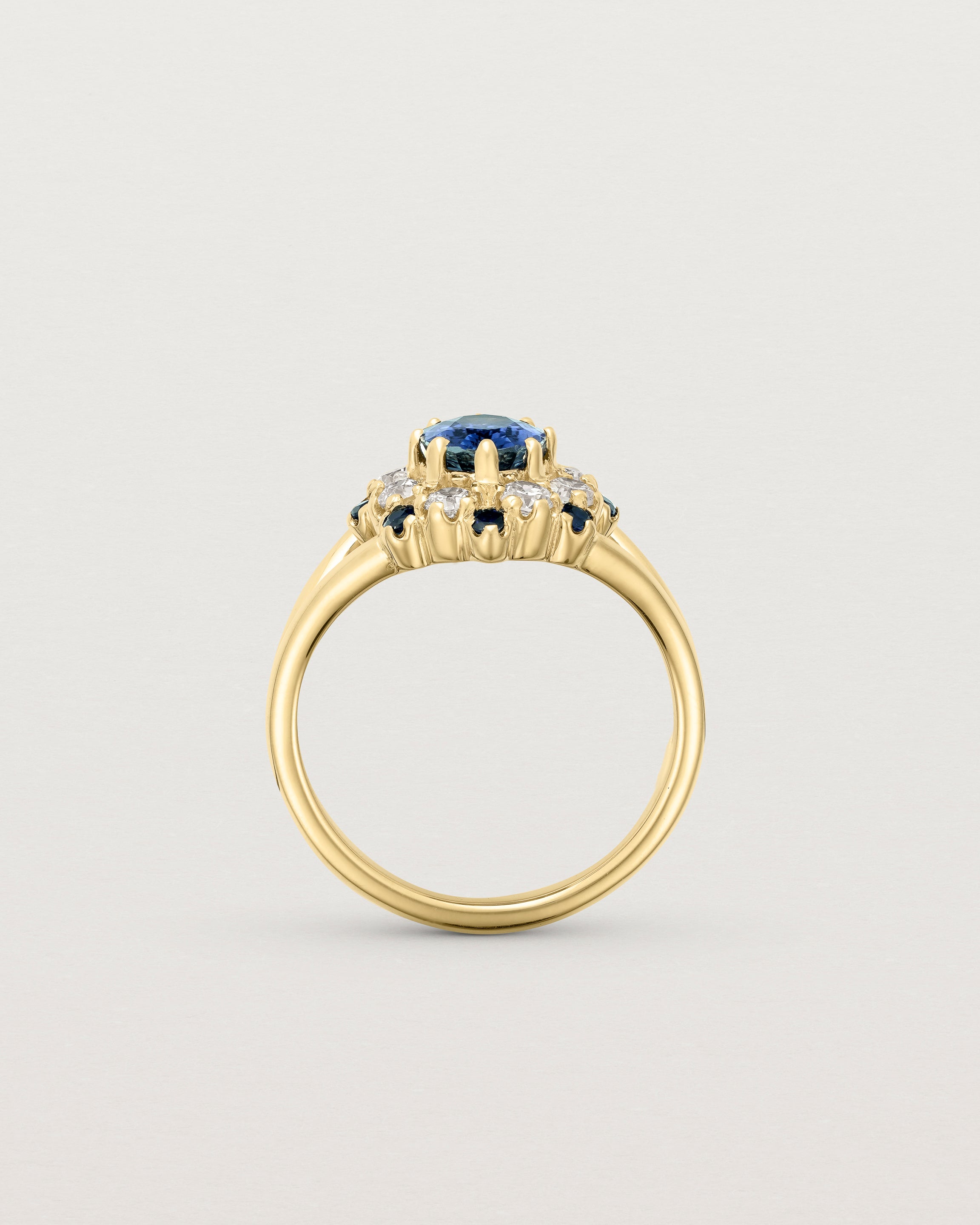 Standing deep etched image of a yellow gold vintage inspired ring with an oval Ceylon Sapphire and a tiered halo of Old Cut Diamonds and Australian Sapphires.