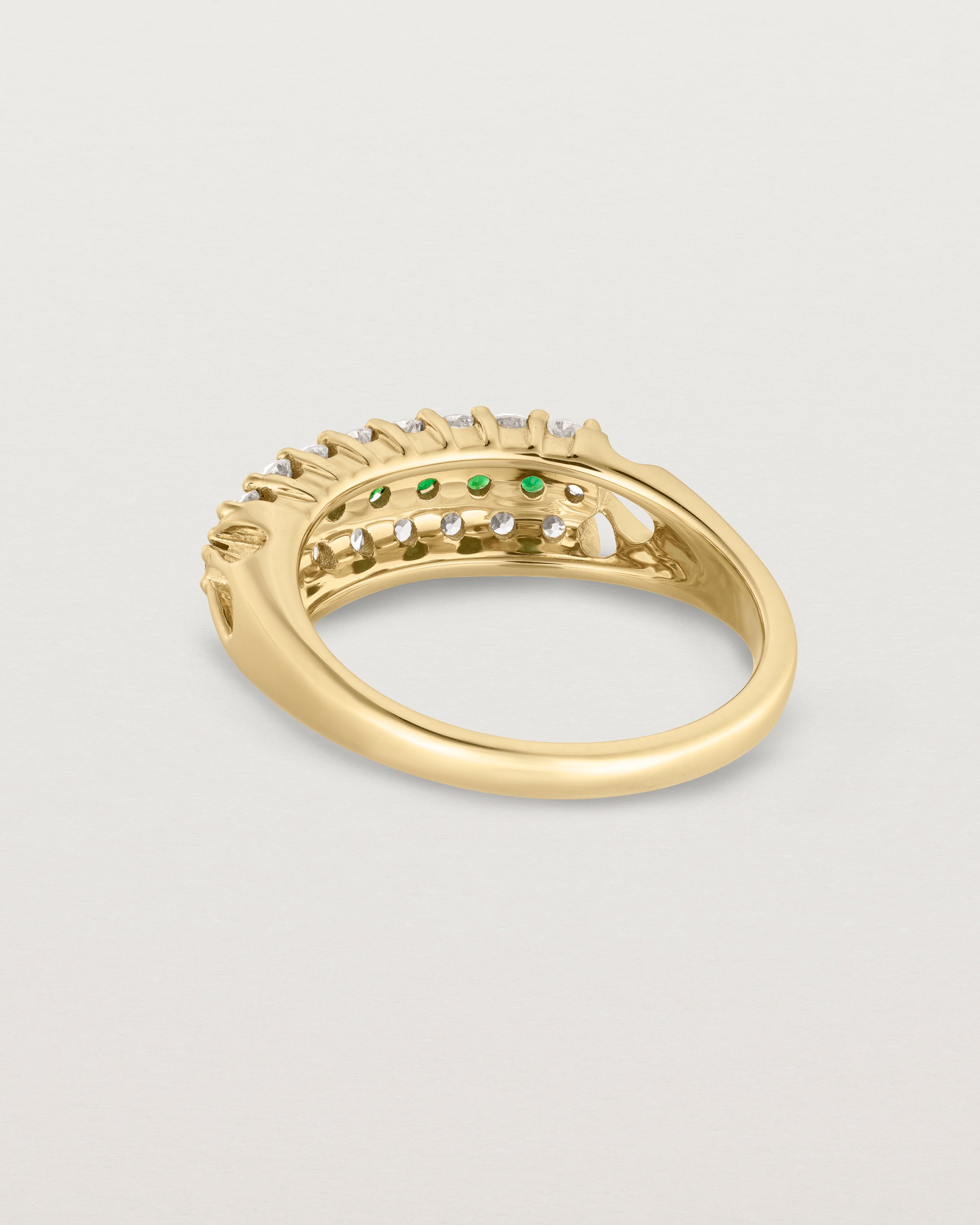 Back facing deep etched image of a yellow gold vintage inspired wrap ring with seven green emeralds and a graduation of 18 old cut diamonds.