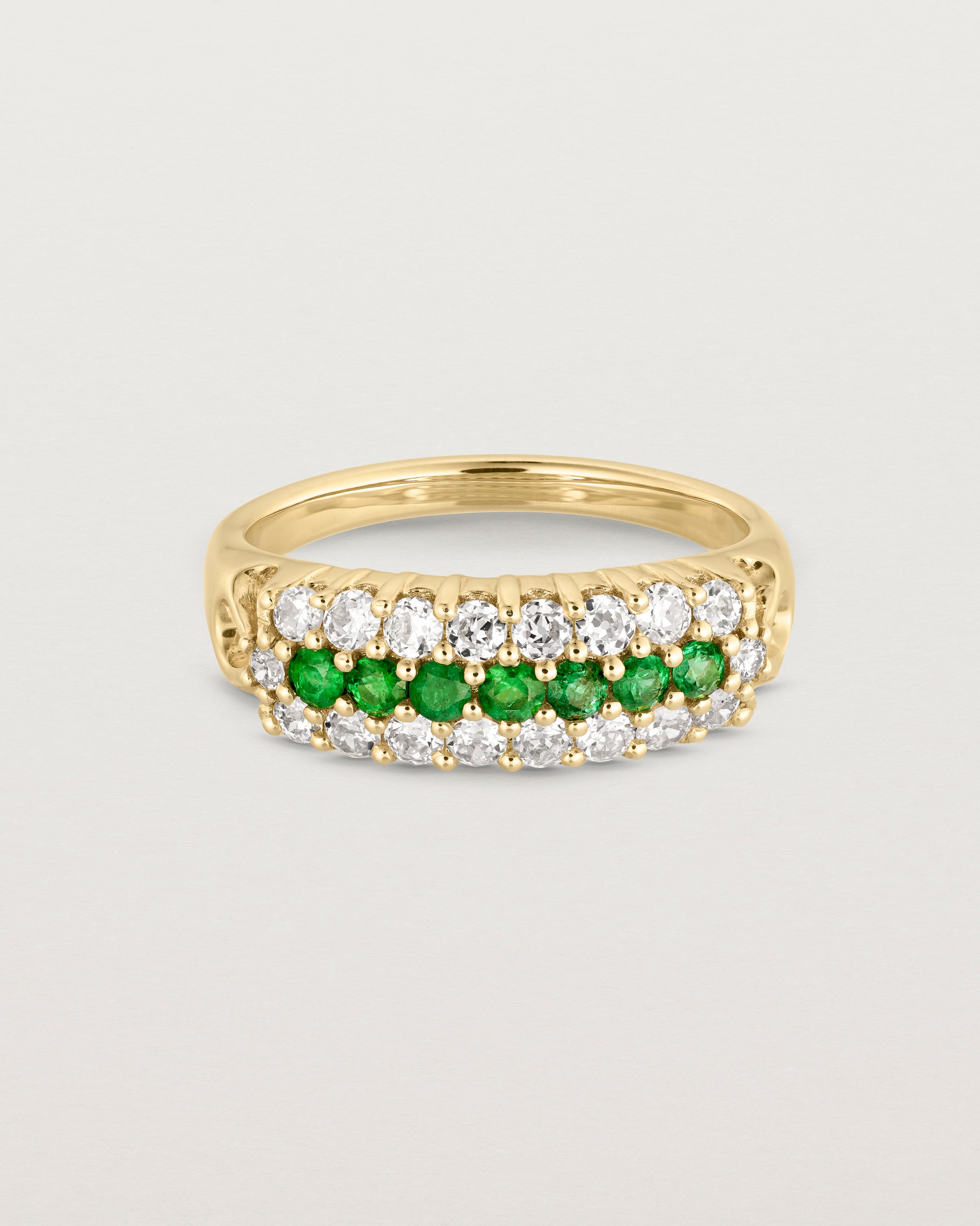 Front facing deep etched image of a yellow gold vintage inspired wrap ring with seven green emeralds and a graduation of 18 old cut diamonds.