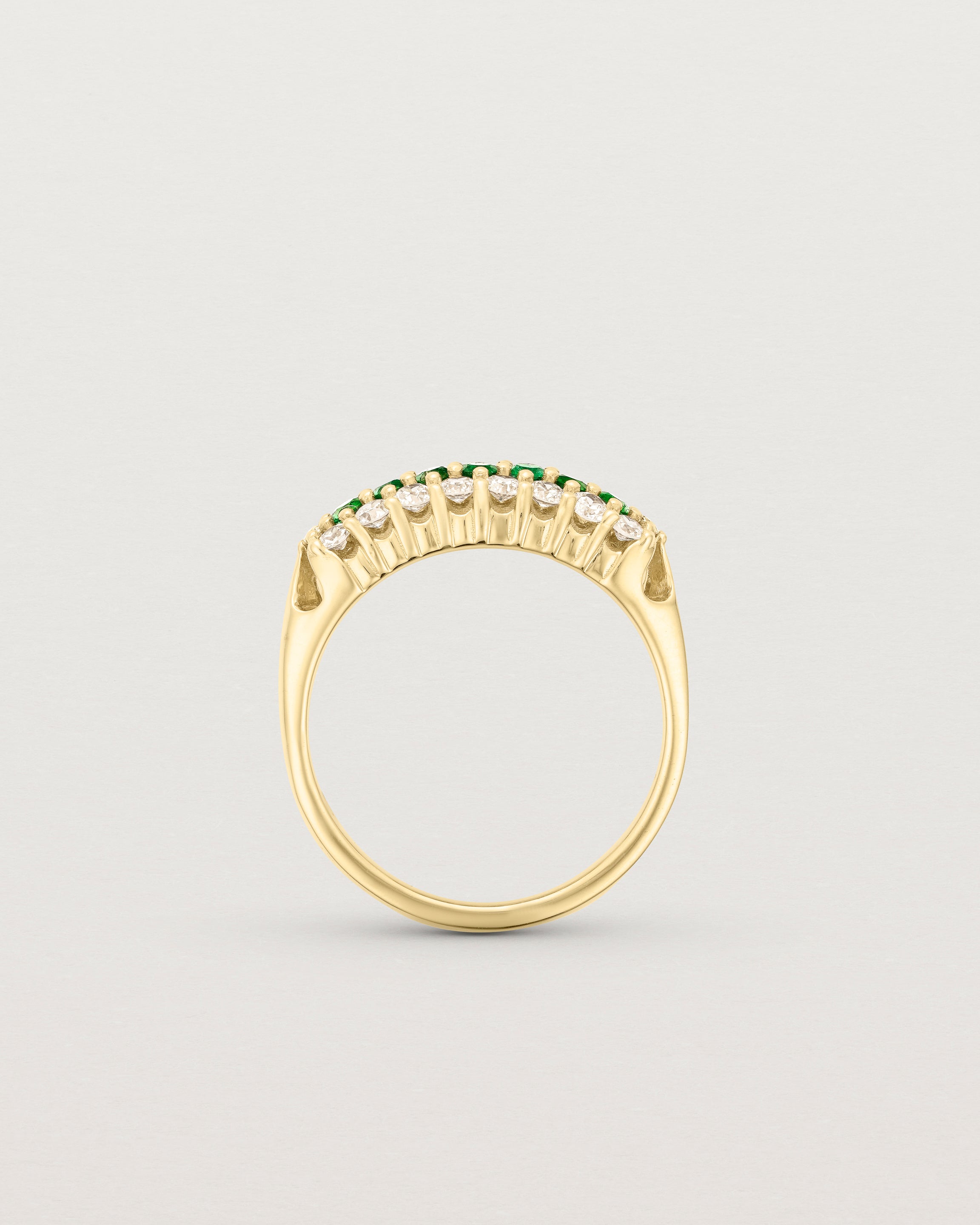 Standing deep etched image of a yellow gold vintage inspired wrap ring with seven green emeralds and a graduation of 18 old cut diamonds.