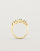 Standing deep etched image of a yellow gold vintage inspired wrap ring with seven green emeralds and a graduation of 18 old cut diamonds.