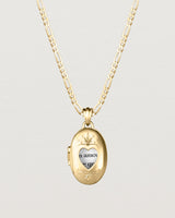 Front facing deep etched image of a yellow gold chain with locket featuring intricate engraving framing a heart shaped window into the locket.