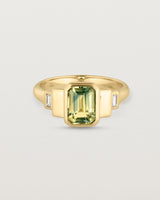 Front facing deep etched image of a yellow gold vintage inspired ring with an emerald cut African parti sapphire with graduating layers either side of the central stone and two white diamond baguettes.