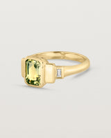 Side facing deep etched image of a yellow gold vintage inspired ring with an emerald cut African parti sapphire with graduating layers either side of the central stone and two white diamond baguettes.