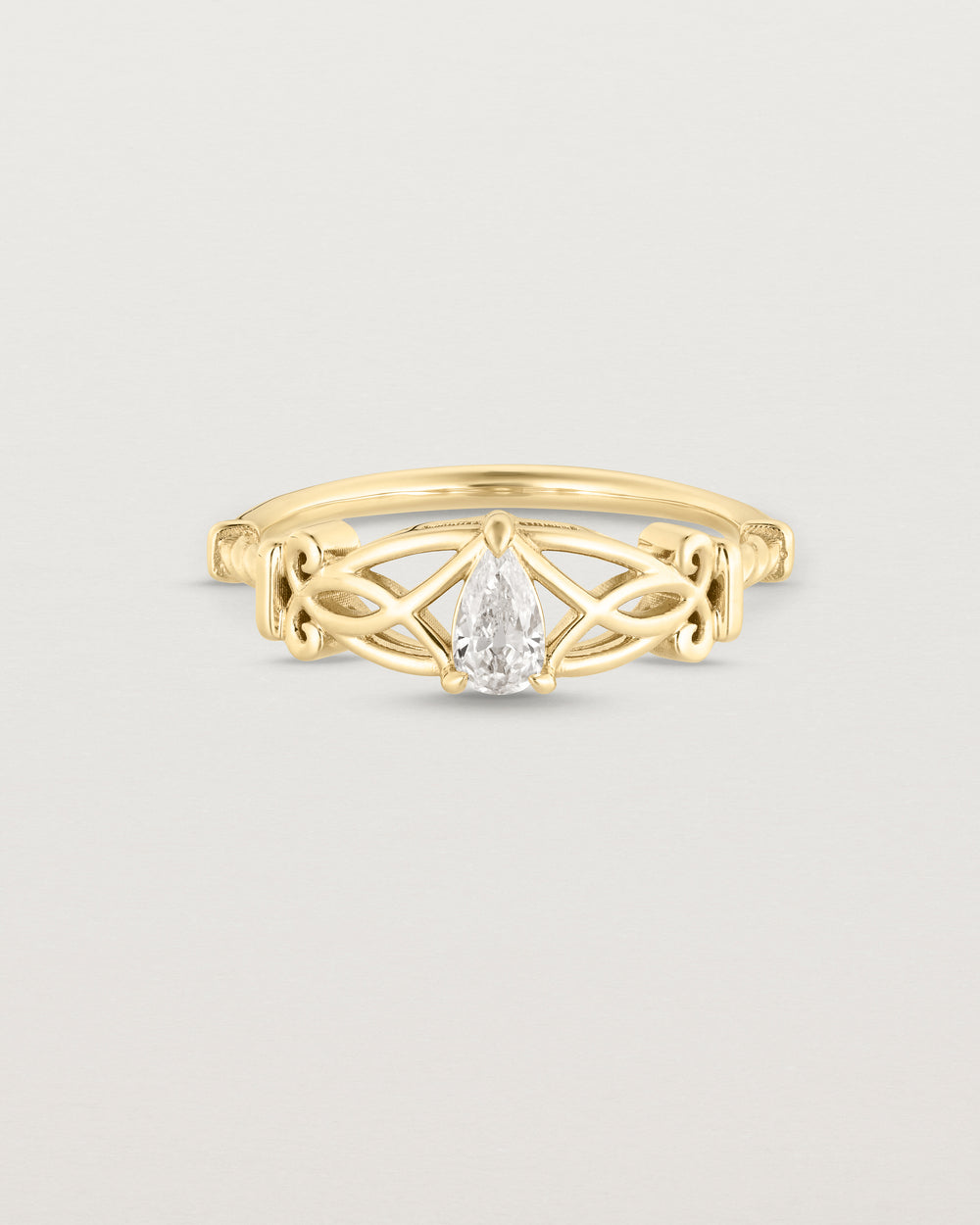 Front facing deep etched image of a vintage inspired yellow gold ring with an old mine cut pear diamond and intricate wire work.