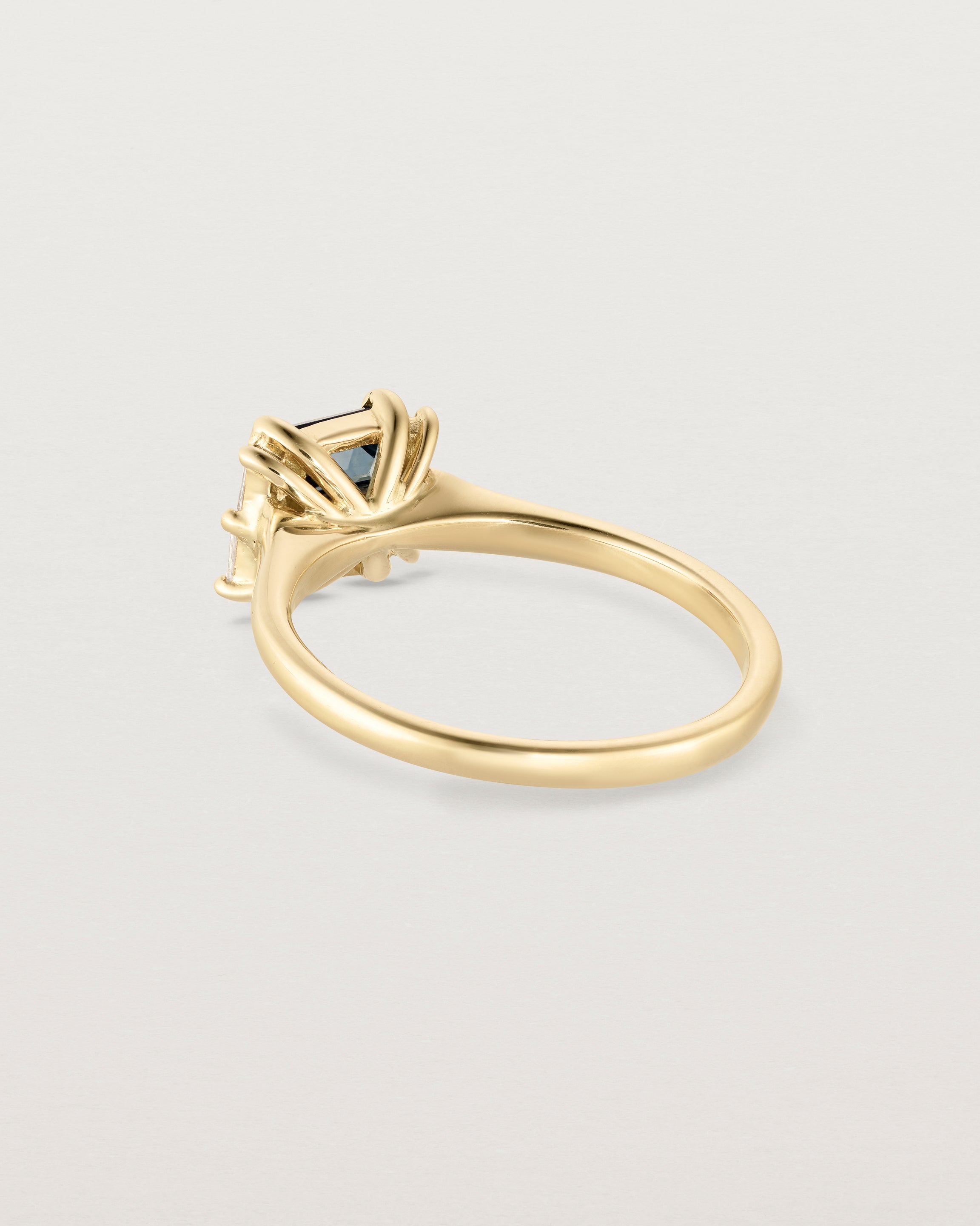 Back facing deep etched image of a yellow gold trio design engagement ring. 