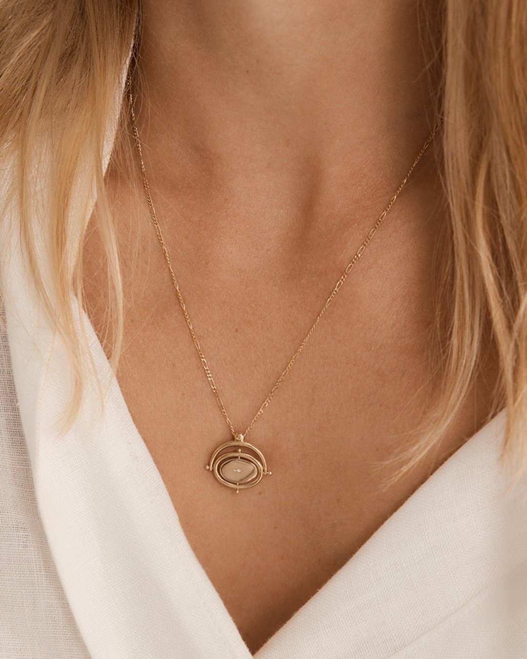 Woman wears Ora Necklace in yellow gold with birthstone.