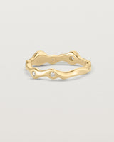 Back facing deep etched image of a yellow gold ring with seven scattered white diamonds.