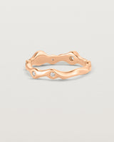 Back facing deep etched image of a rose gold ring with seven scattered white diamonds.