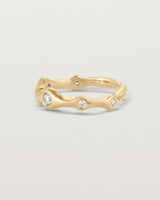 Side facing deep etched image of a yellow gold ring with seven scattered white diamonds.