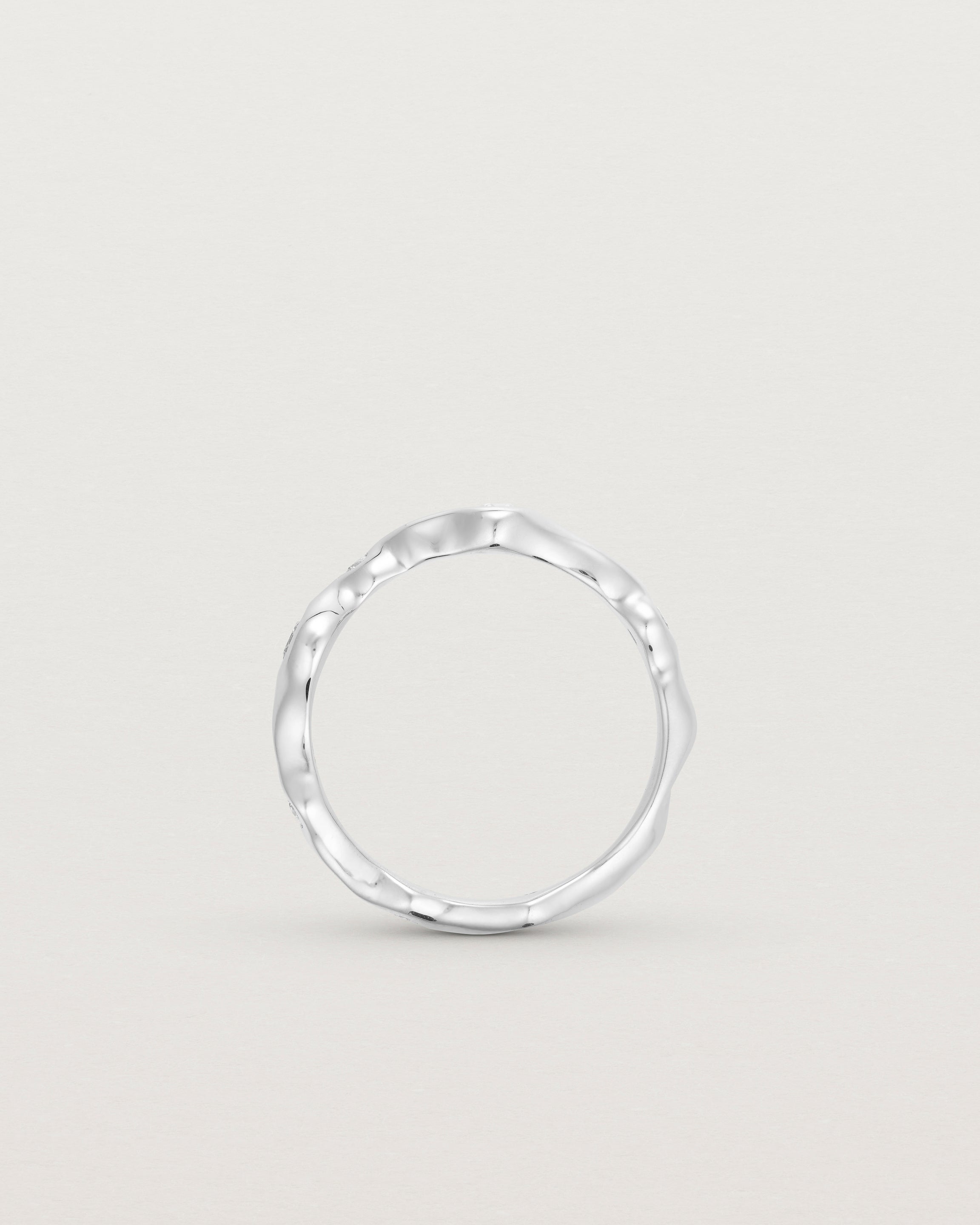 Standing deep etched image of a white gold ring with seven scattered white diamonds.