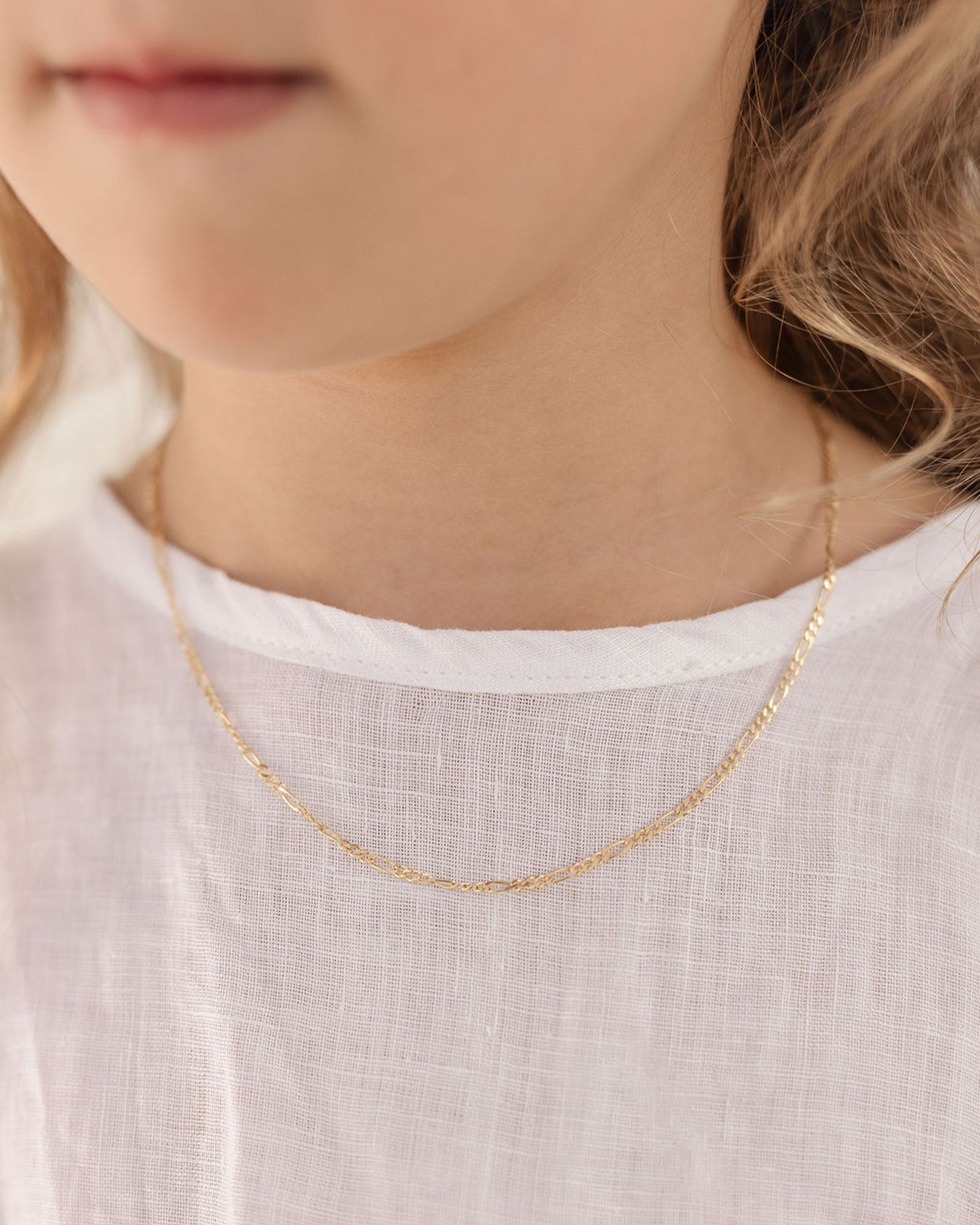 Front of image of the Petit Figaro chain in yellow gold being worn by a girl model