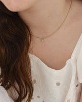 close up image of the Starburst Diamond necklace in yellow gold, being worn on a child model