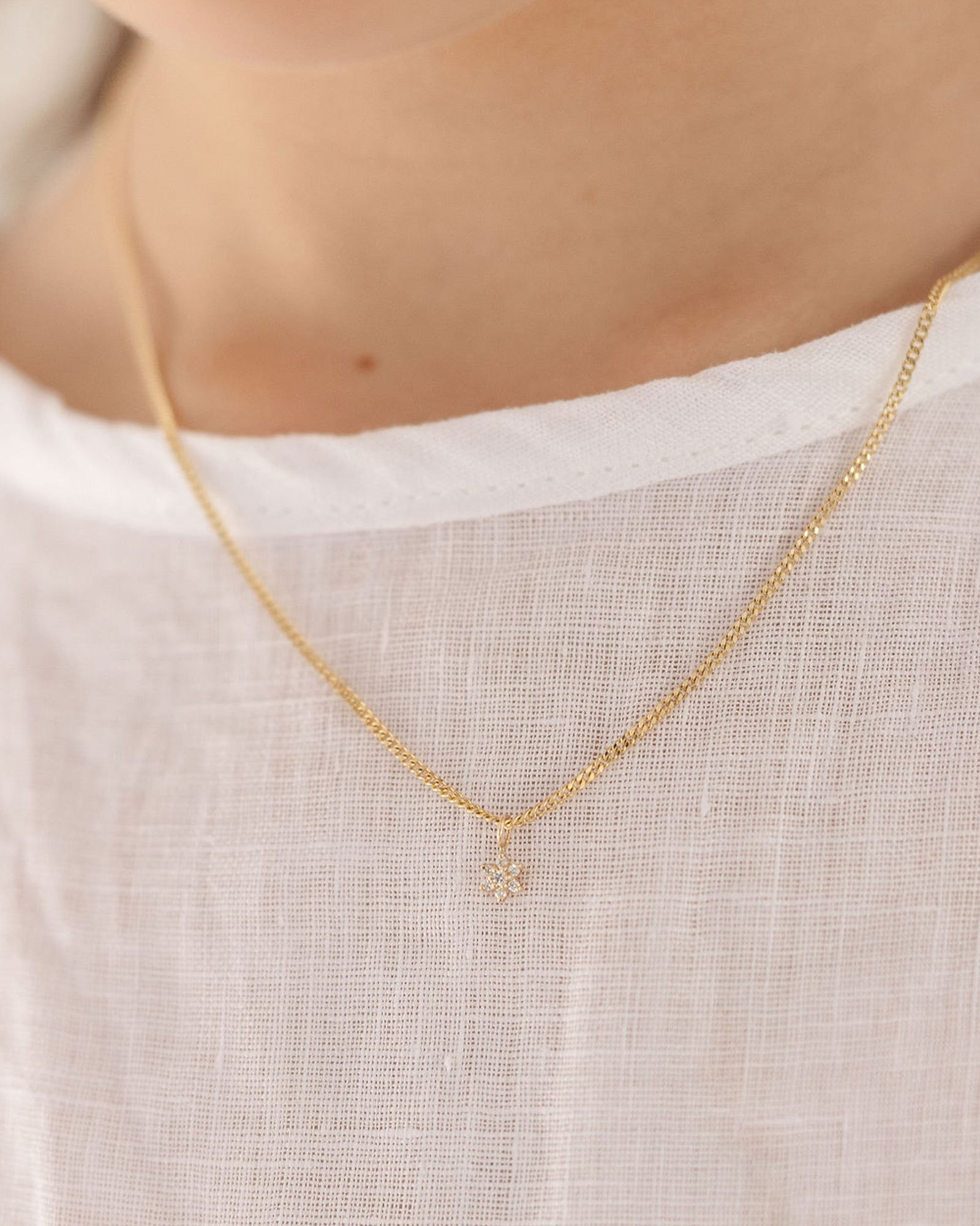 clos eup image of the Starburst Diamond necklace in yellow gold, being worn on a child model