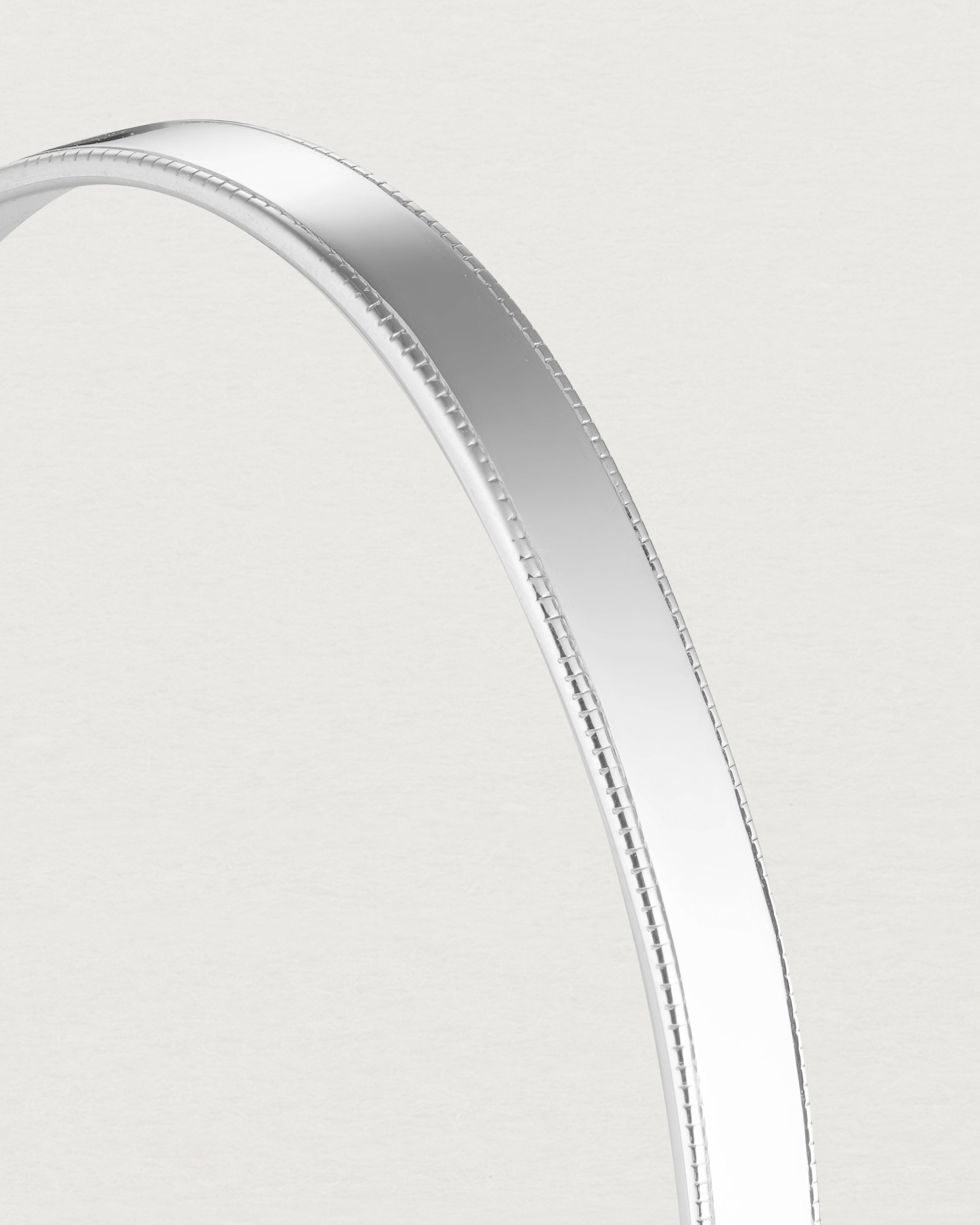 close up image of the Toujours Bangle with millgrain in Sterling Silver