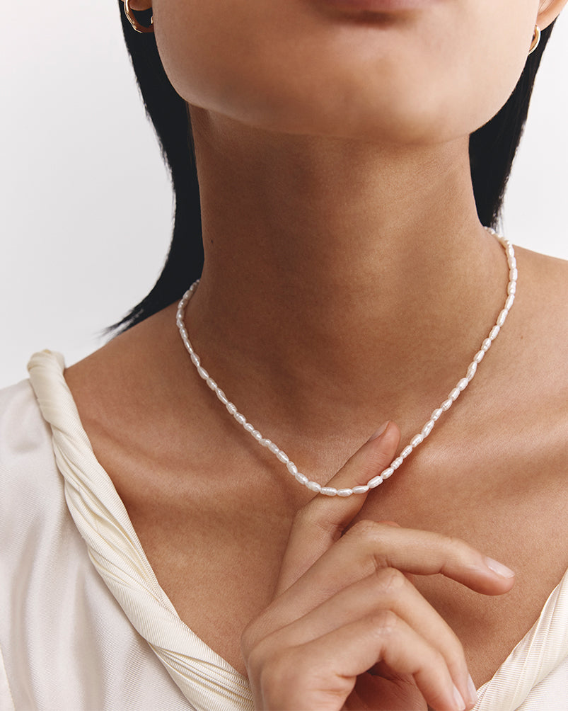 Image of a woman wearing a singular pearl necklace