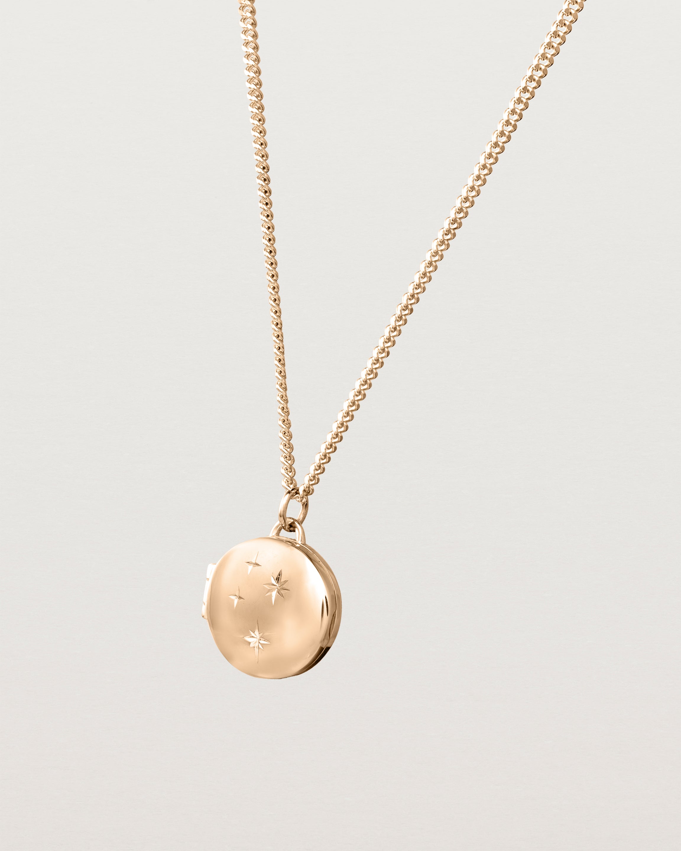 Side image of the starburst locket in rose gold.