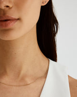 A woman wears the Simple Chain Necklace in yellow gold