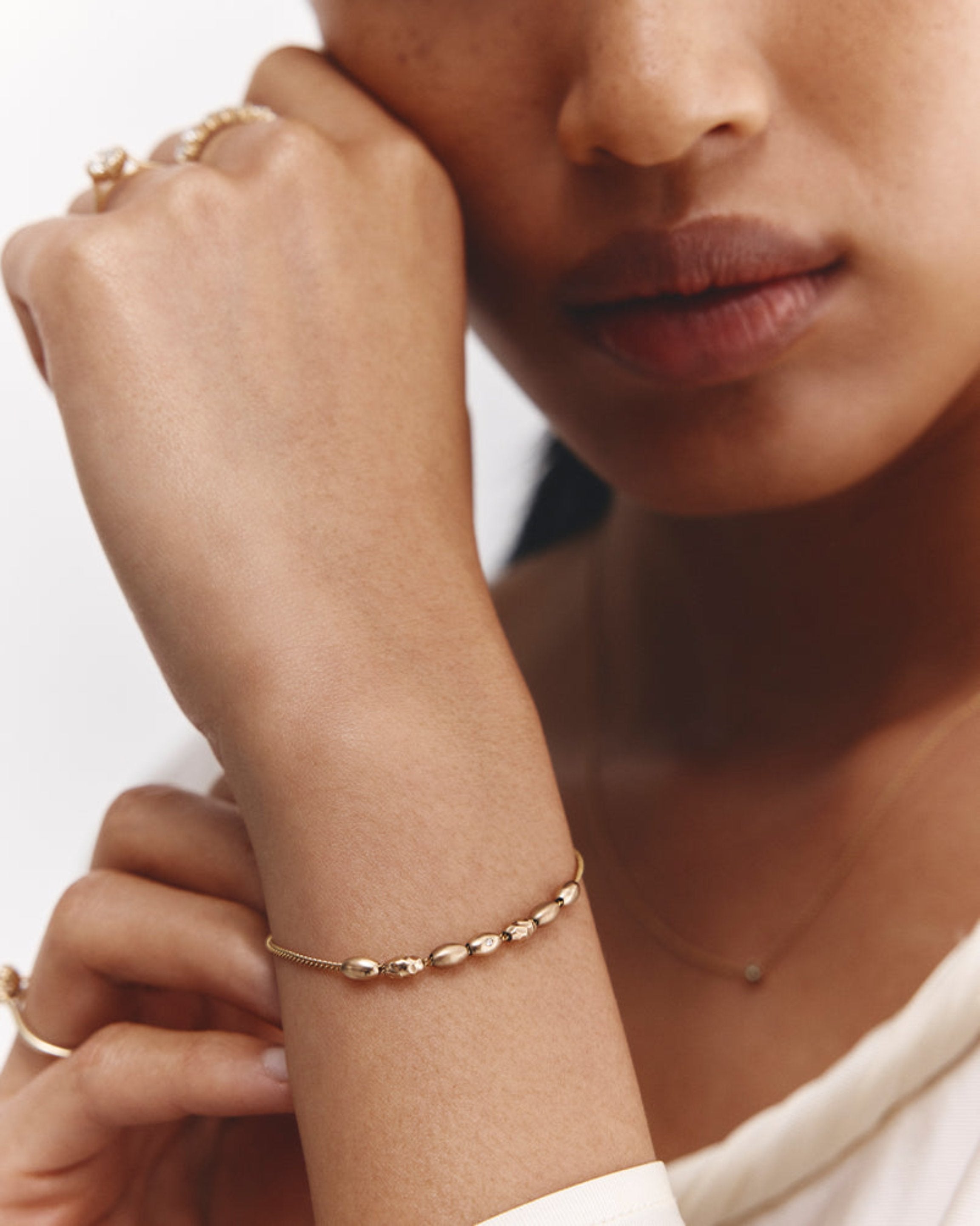 Model wearing Sonder Bracelet in yellow gold with different charms.